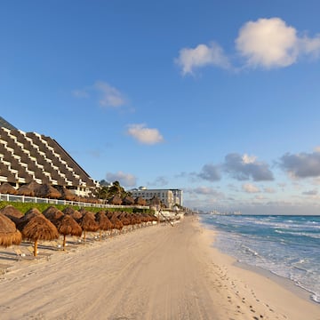 a beach with straw umbrellas and a building in the background