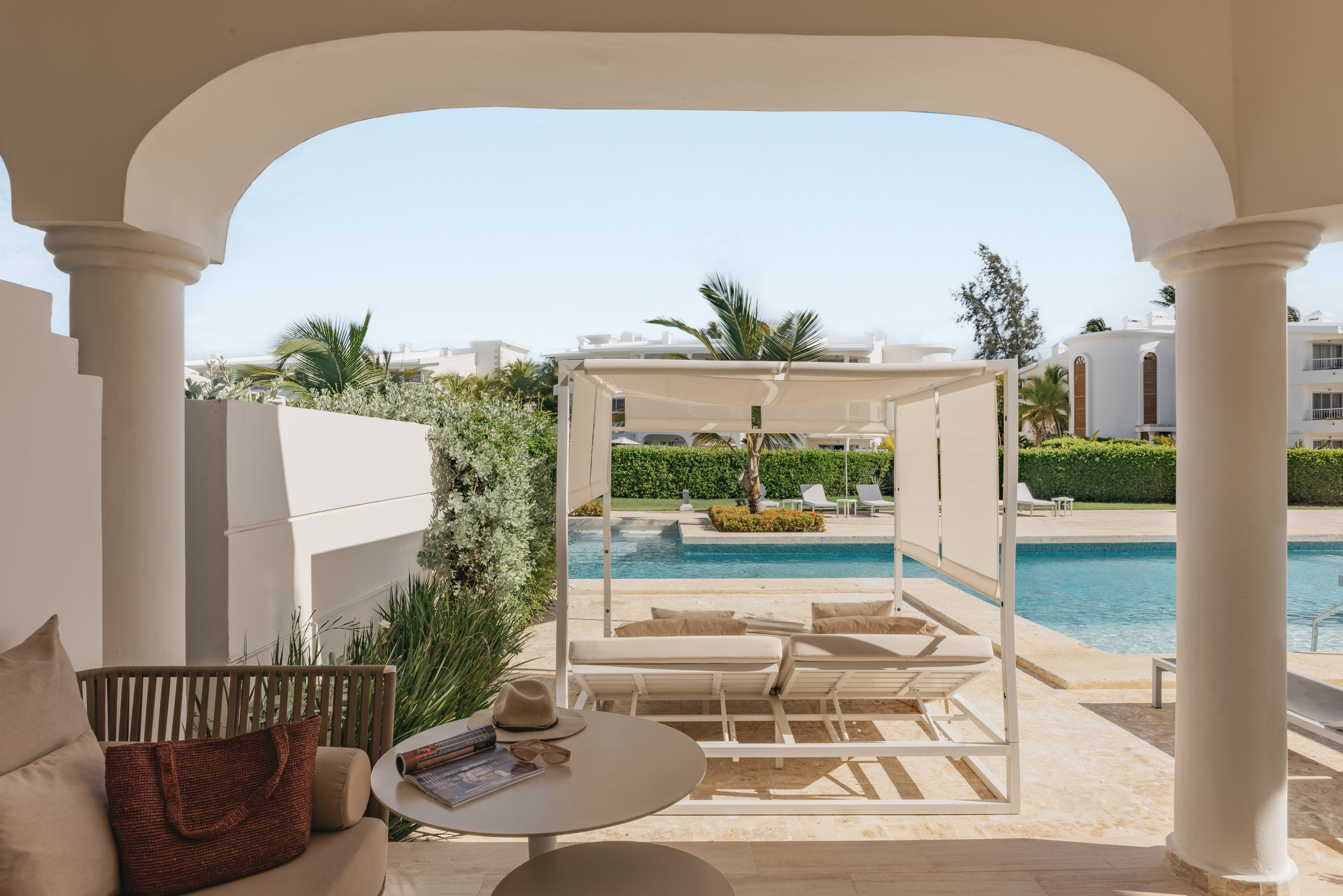Luxury resort patio with swimming pool, white cabana, and tropical palms.