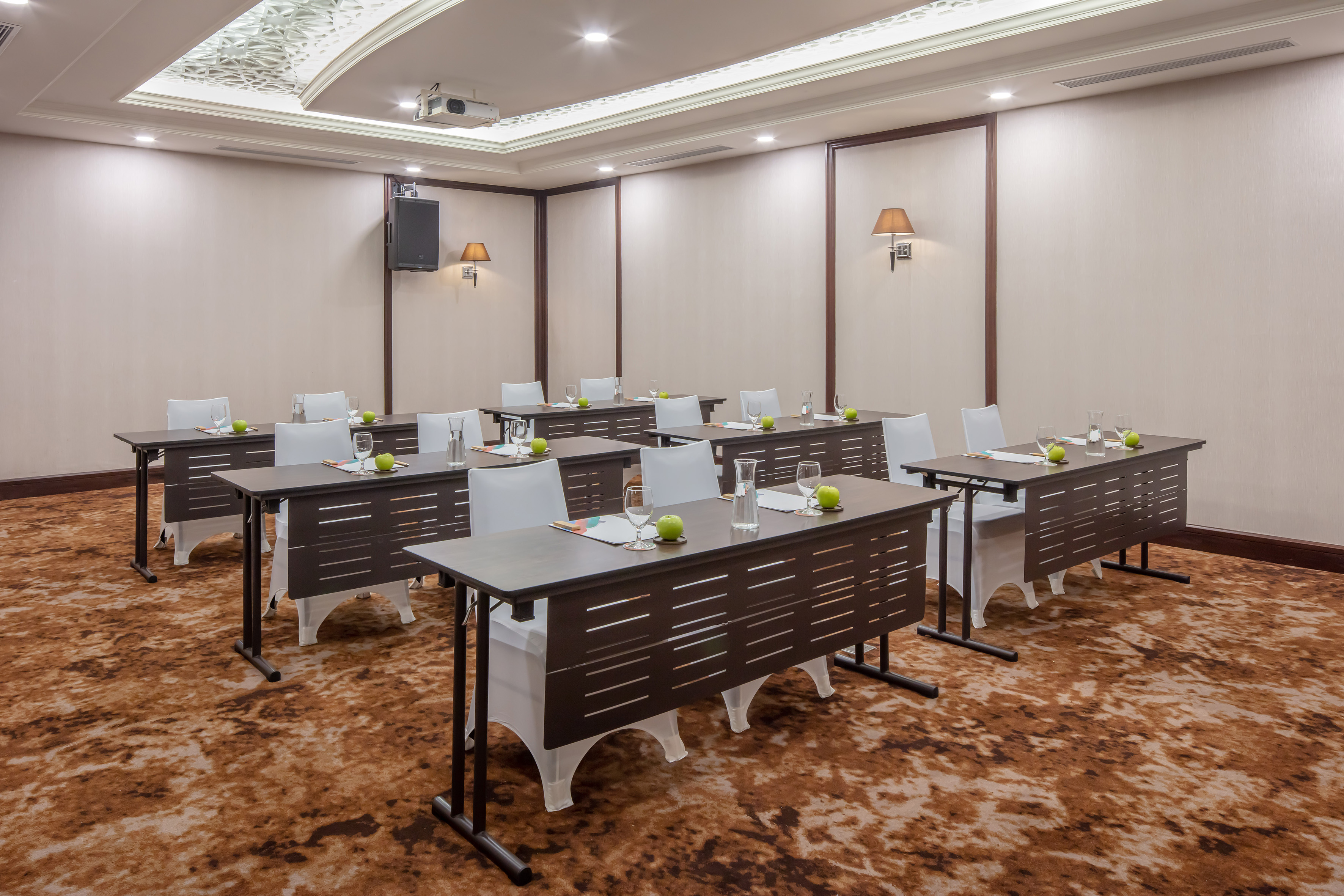 Classroom style conference room, dark tables, white chairs, projector.