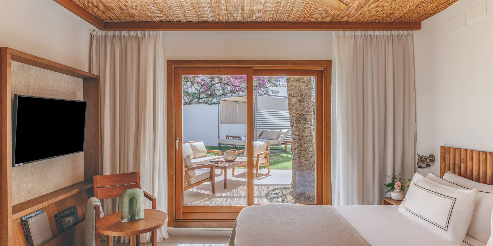 Resort bedroom with bamboo ceiling, wooden fan, and private patio garden.