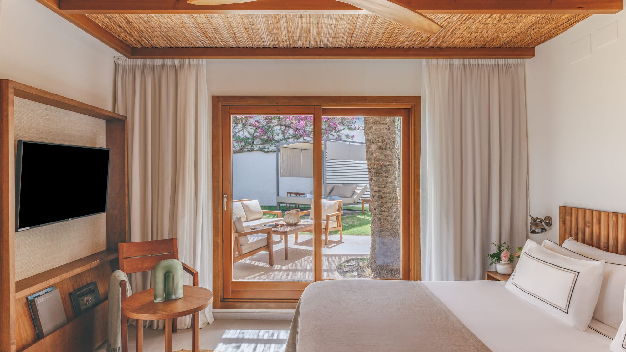 Resort bedroom with bamboo ceiling, wooden fan, and private patio garden.