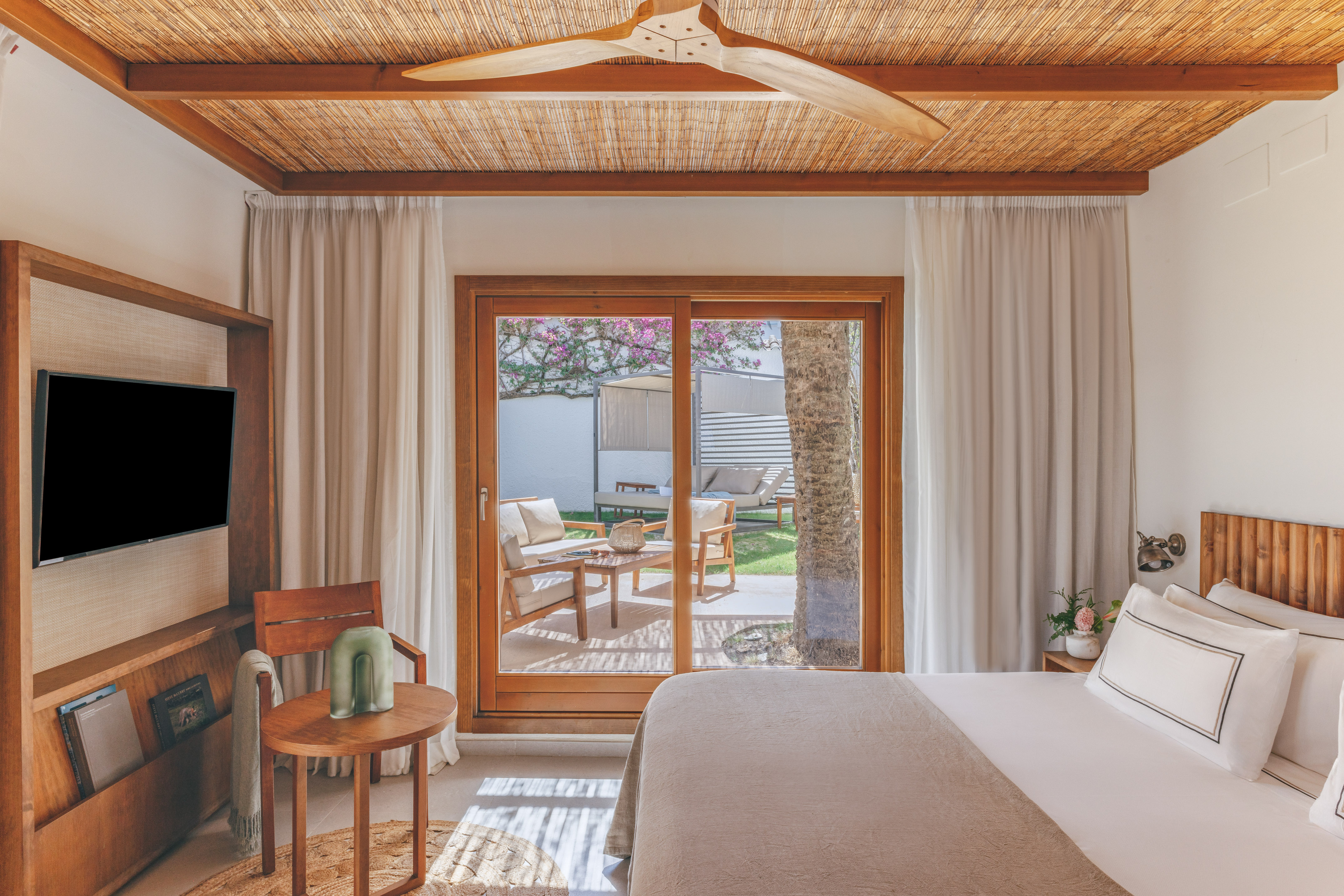 Resort bedroom with bamboo ceiling, wooden fan, and private patio garden.