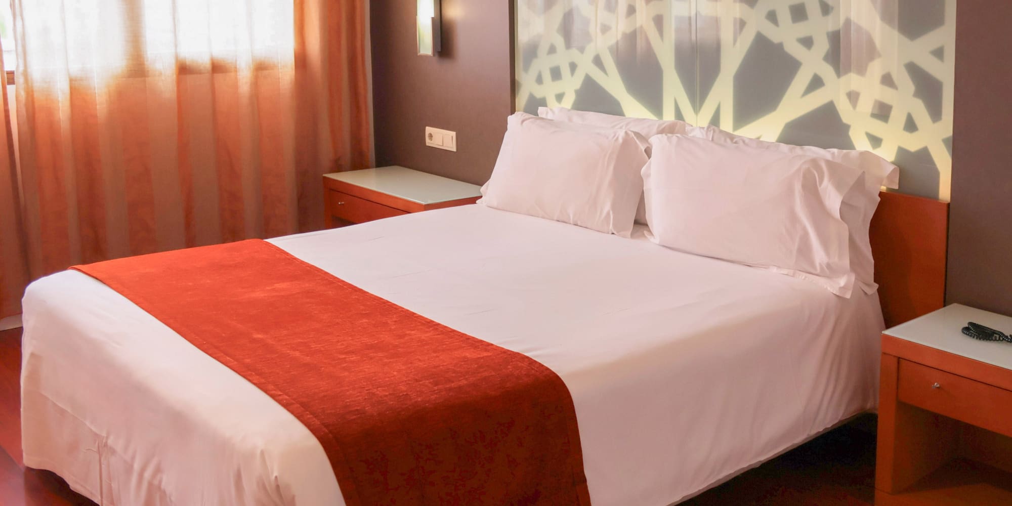 a bed with white sheets and red blanket