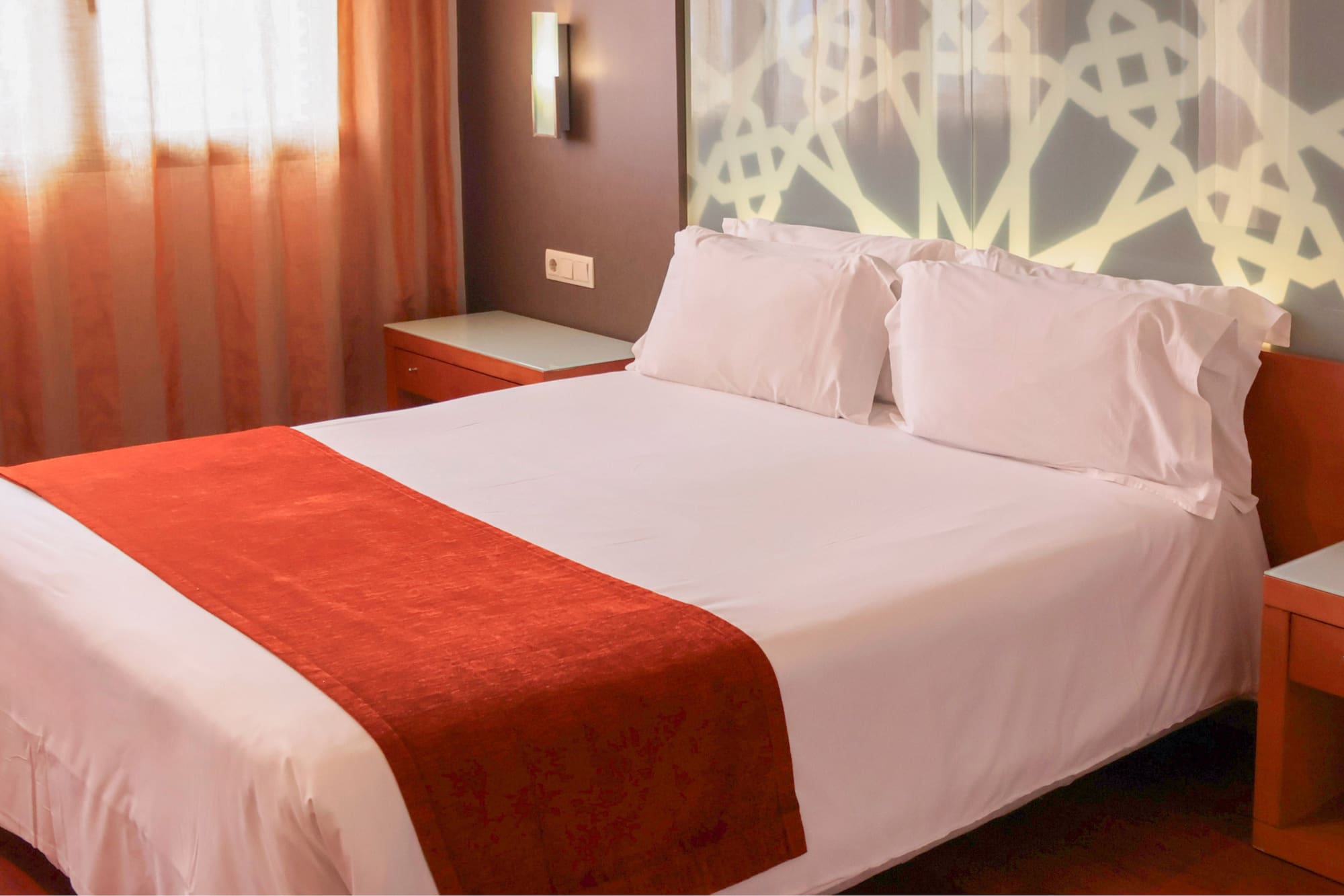 a bed with white sheets and red blanket