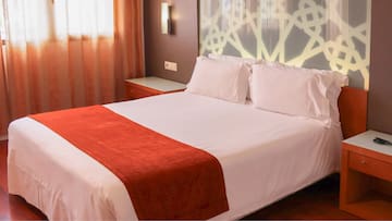 a bed with white sheets and red blanket
