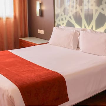 a bed with white sheets and red blanket
