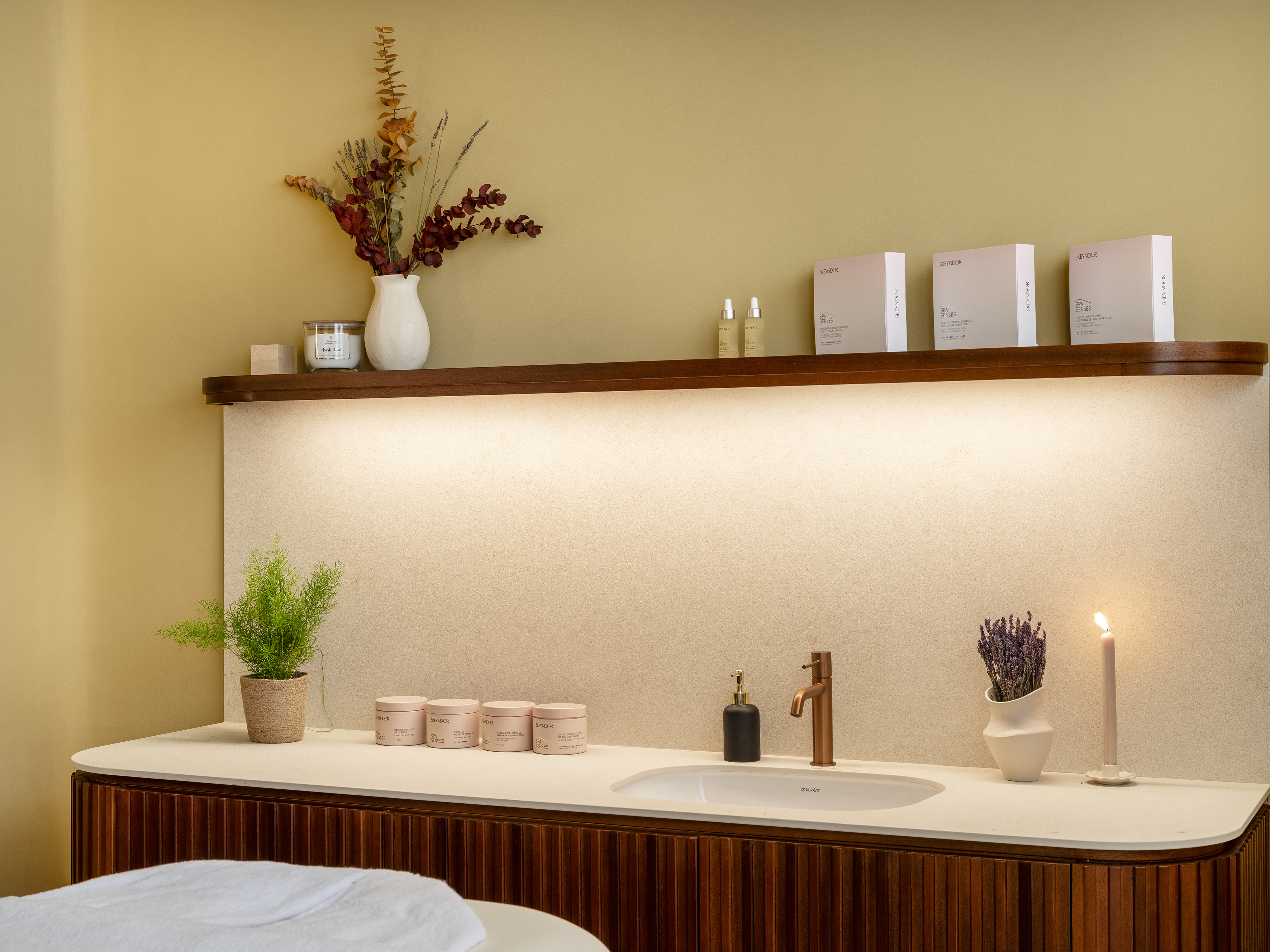 Wellness spa room with Skeyndor products, sink, plant, and glowing candle.