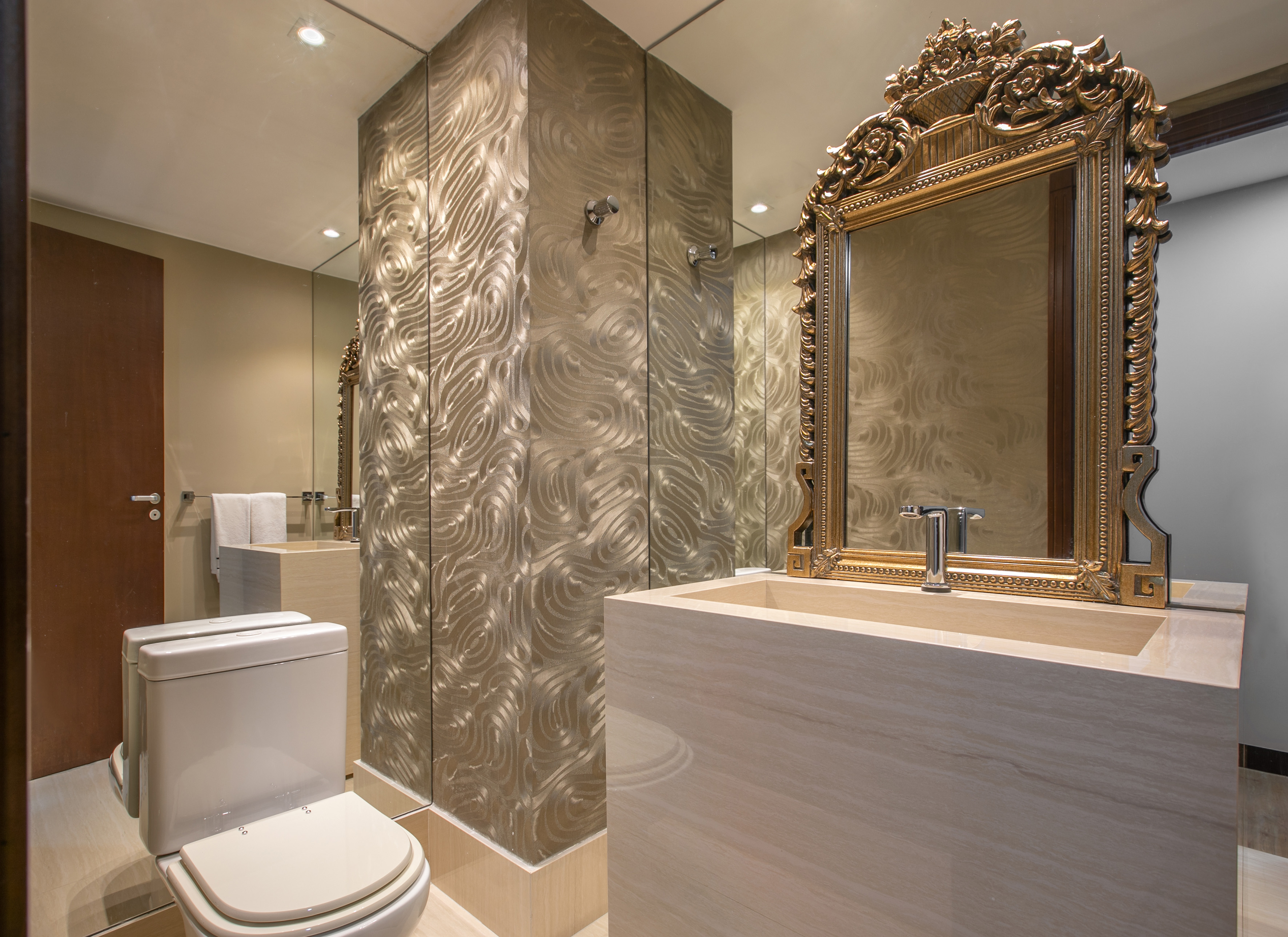 Luxury bathroom with ornate gold mirror, sleek stone vanity, and textured walls.