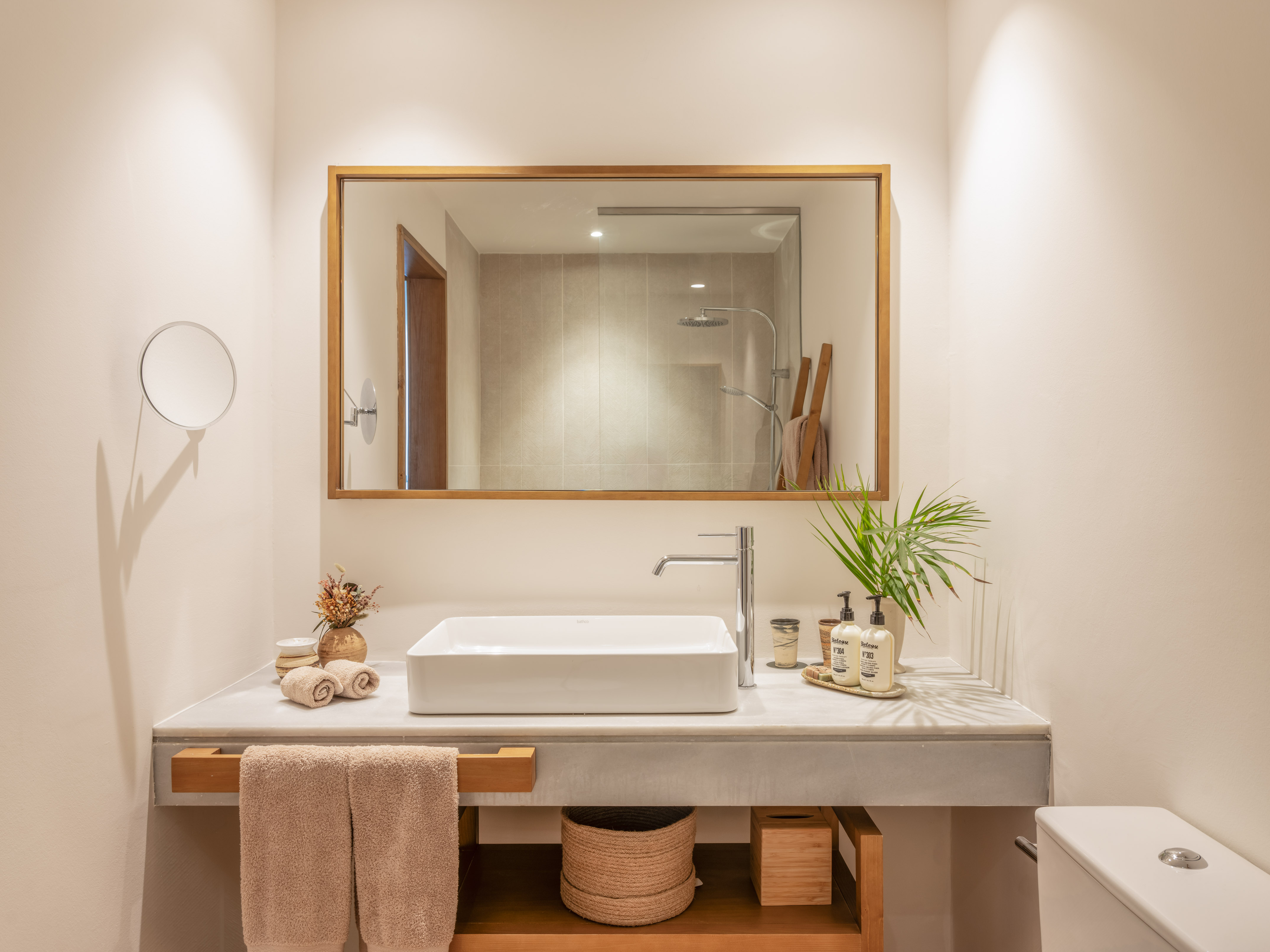 Modern bathroom with rectangular sink, marble vanity, wood mirror, and shower reflection.