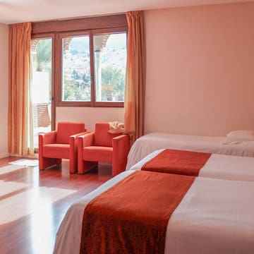 a room with two beds and chairs