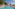 Resort swimming pool with palm trees, lounge chairs, and hotel buildings.