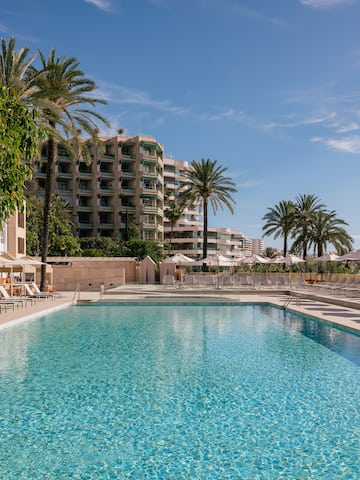 a swimming pool with palm trees and buildings