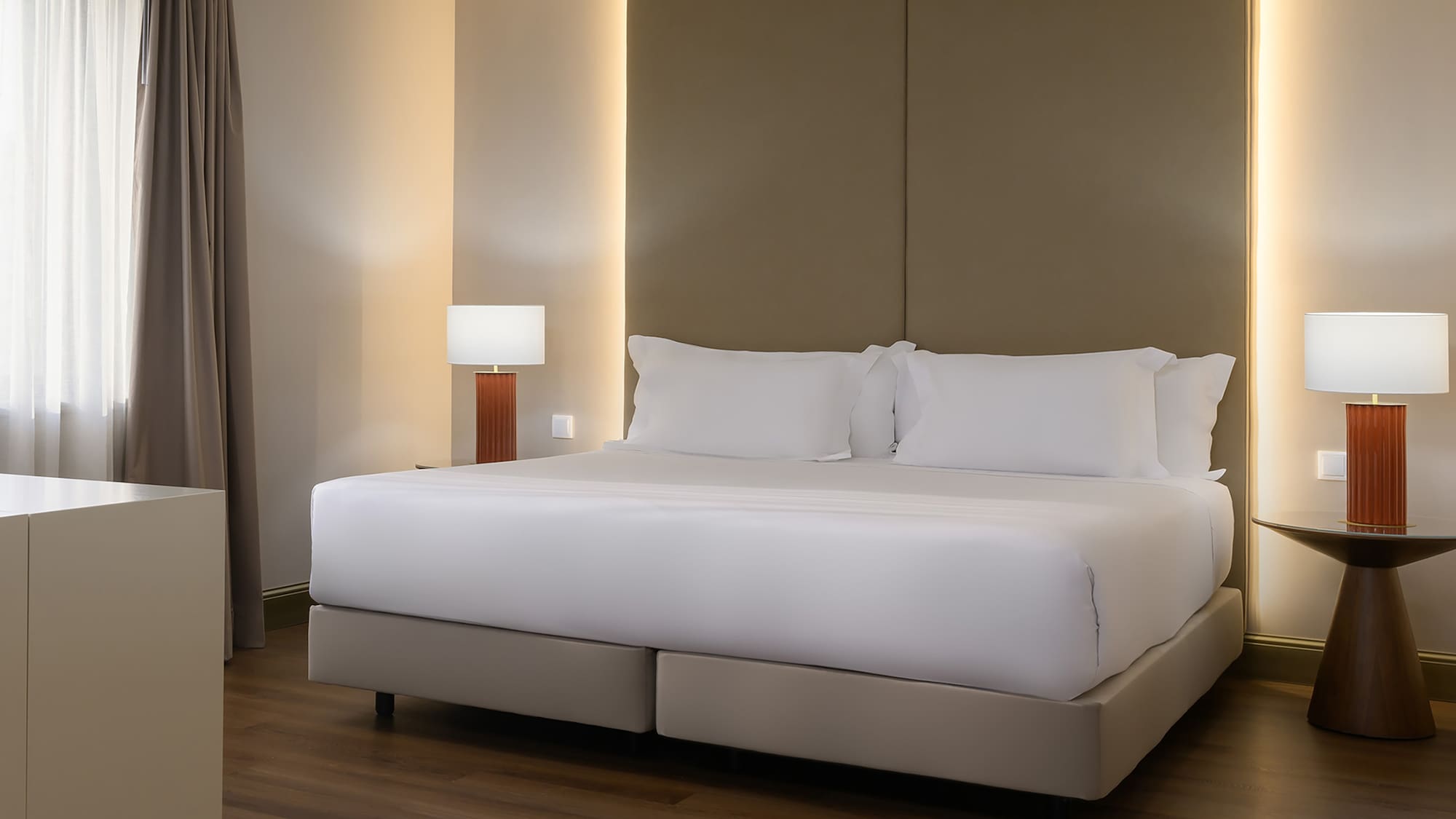 Luxurious hotel bedroom with large bed, padded headboard, and ambient lighting.