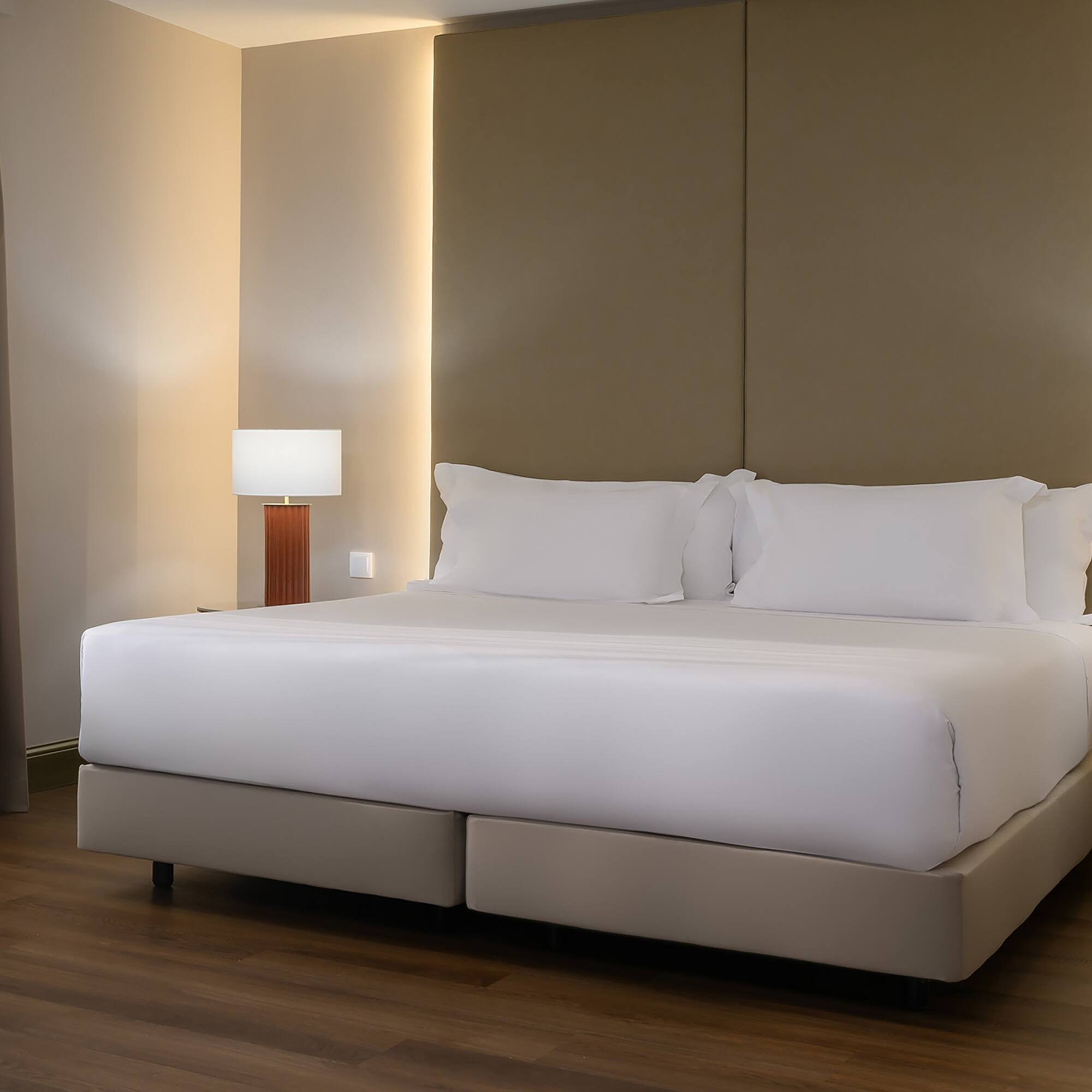 a bed with white sheets and a lamp