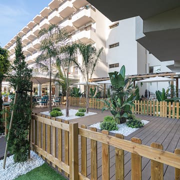 a wooden deck with trees and a fence in front of a building