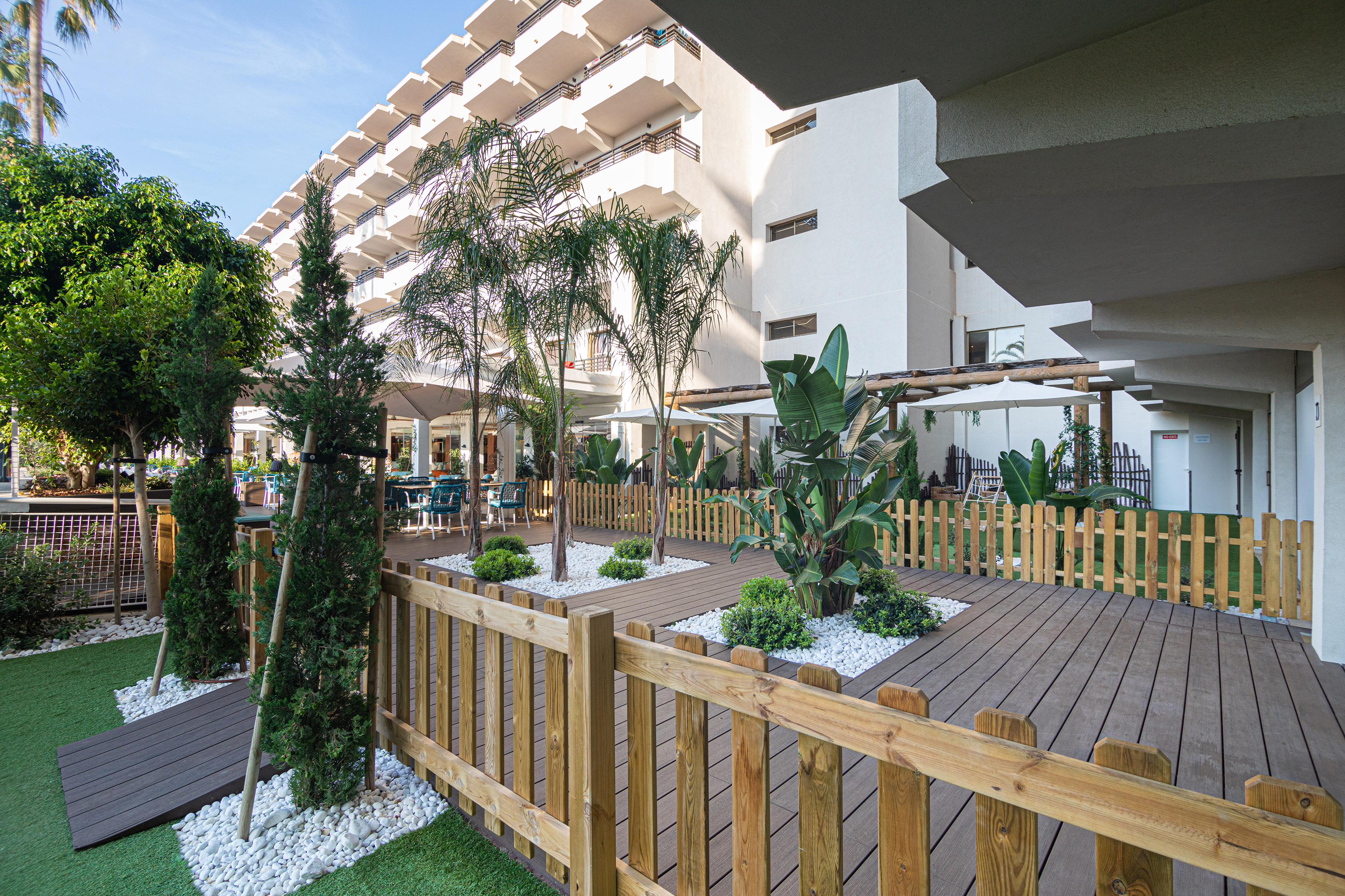 a wooden deck with trees and a fence in front of a building