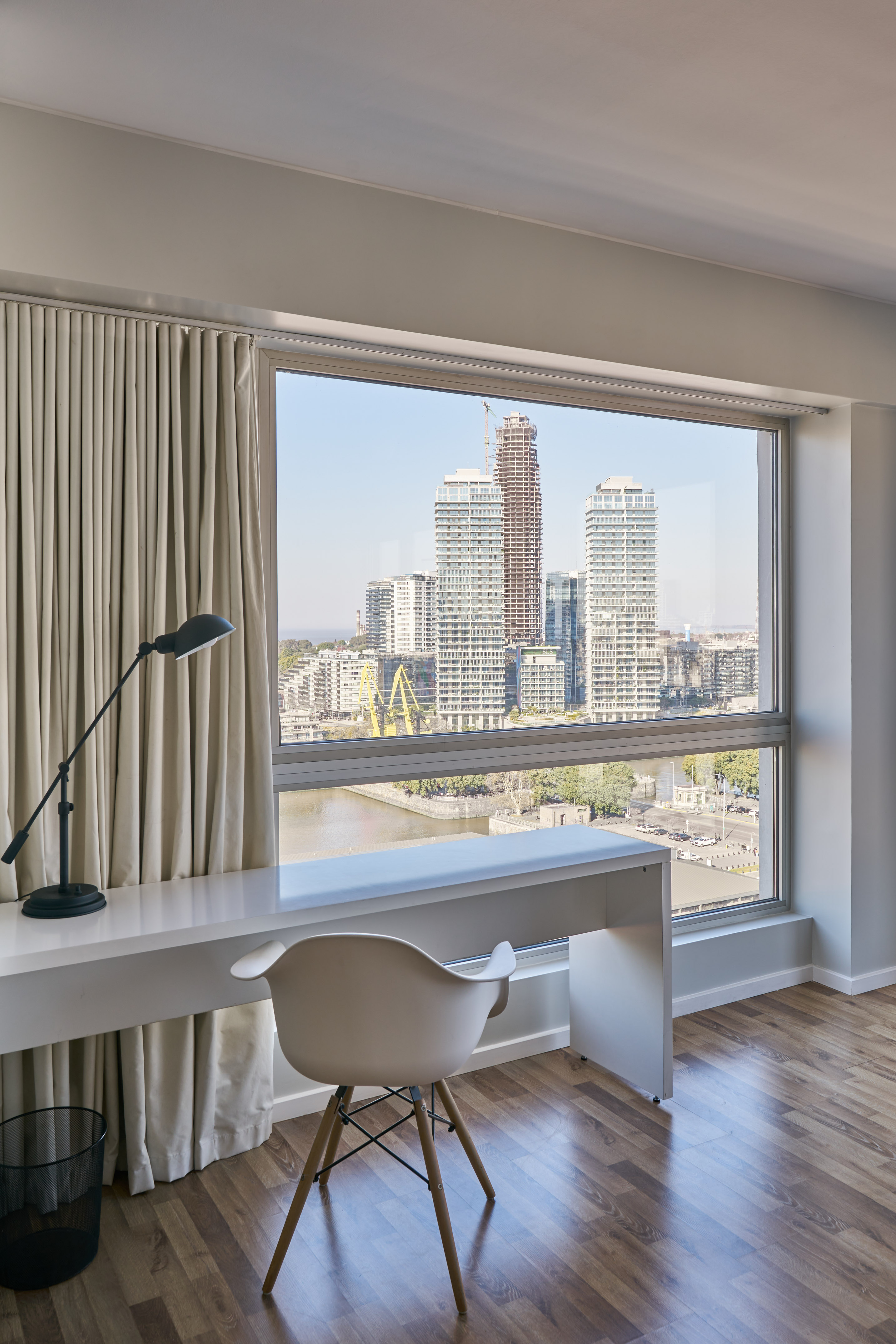 Modern home office desk by window with city skyline and river view.