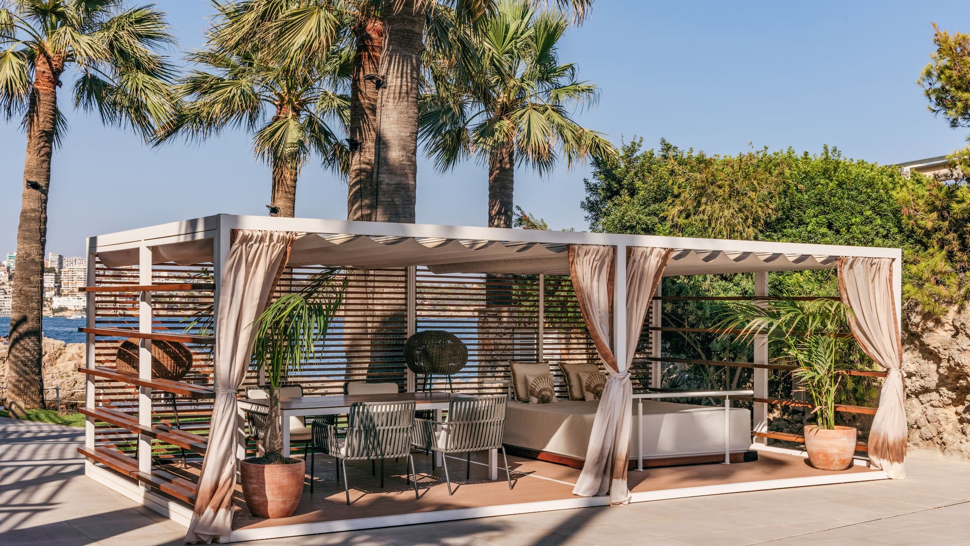 a patio with a bed and chairs under a palm tree