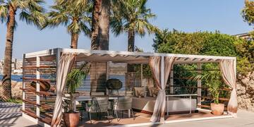 a patio with a bed and chairs under a palm tree