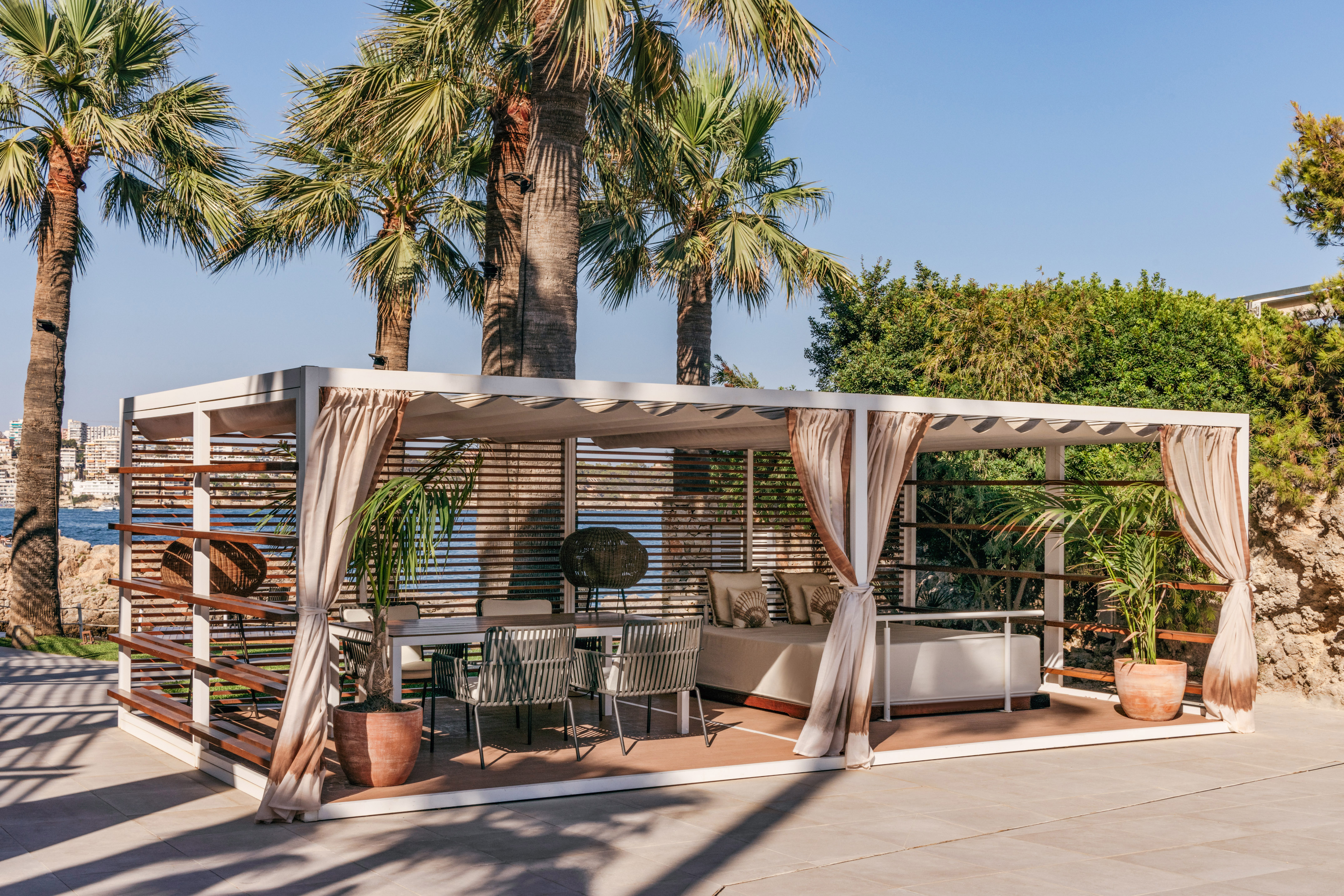 a patio with a bed and chairs under a palm tree
