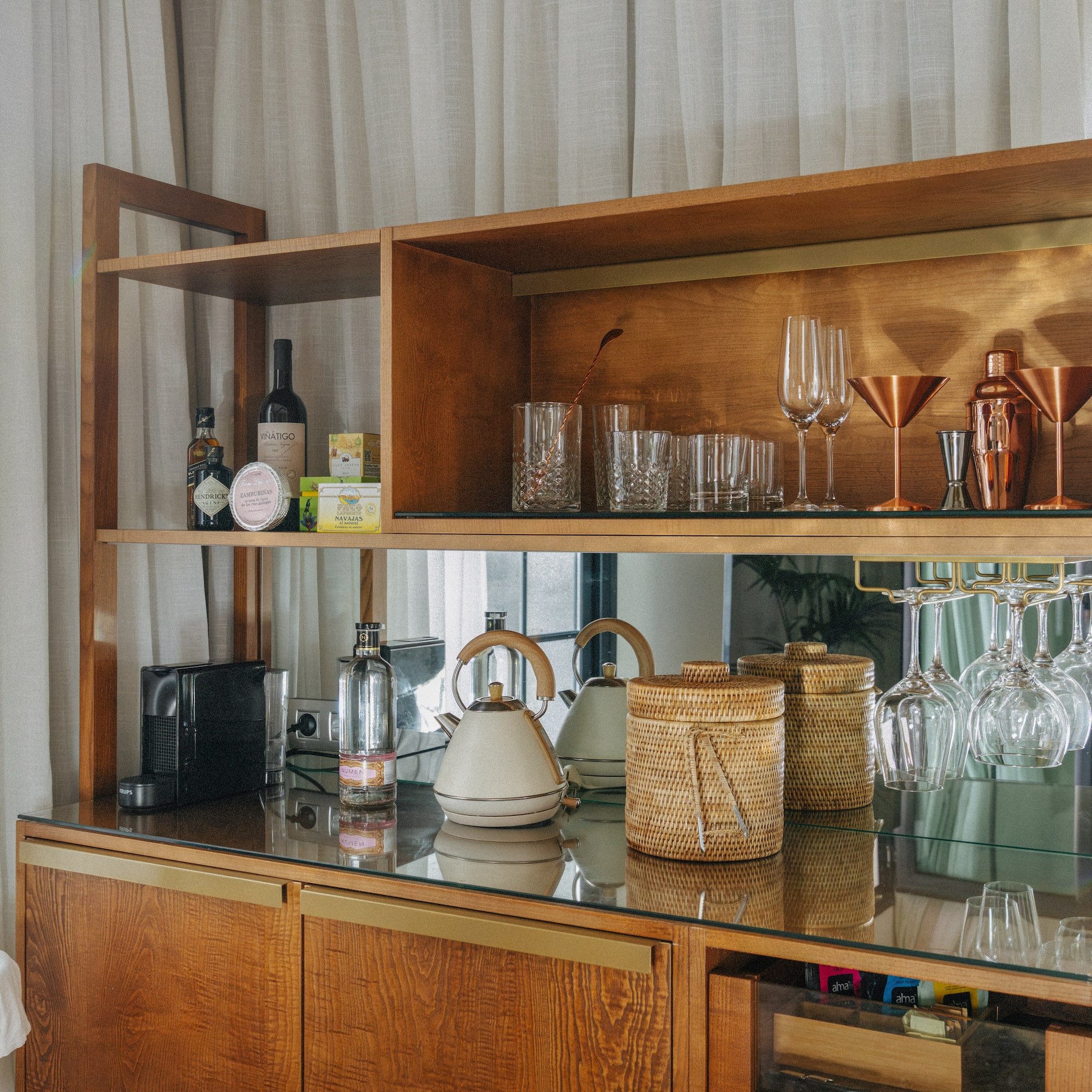 Wooden mini-bar with glassware, spirits, coffee machine, and kettle.