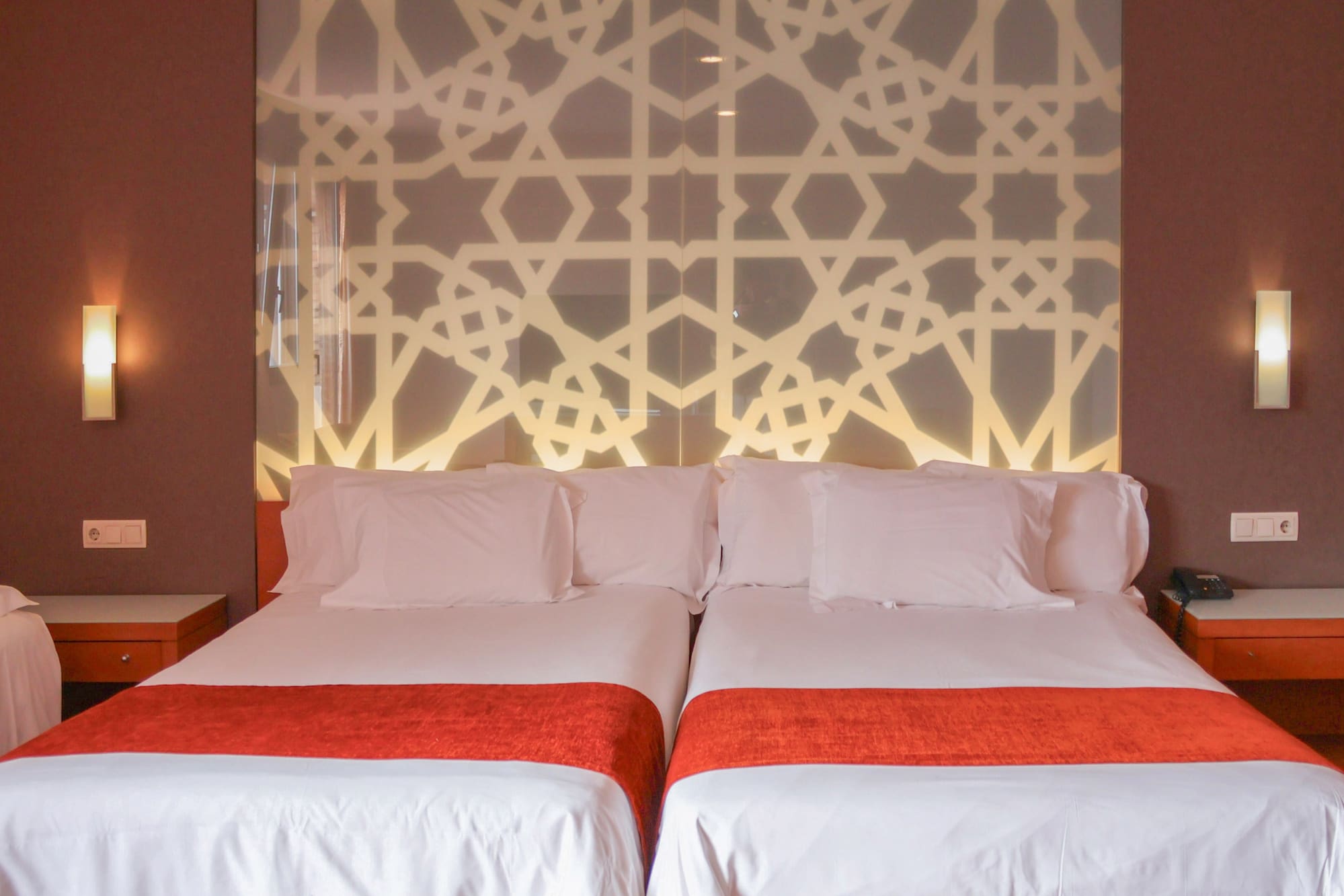 a bed with white sheets and red blankets