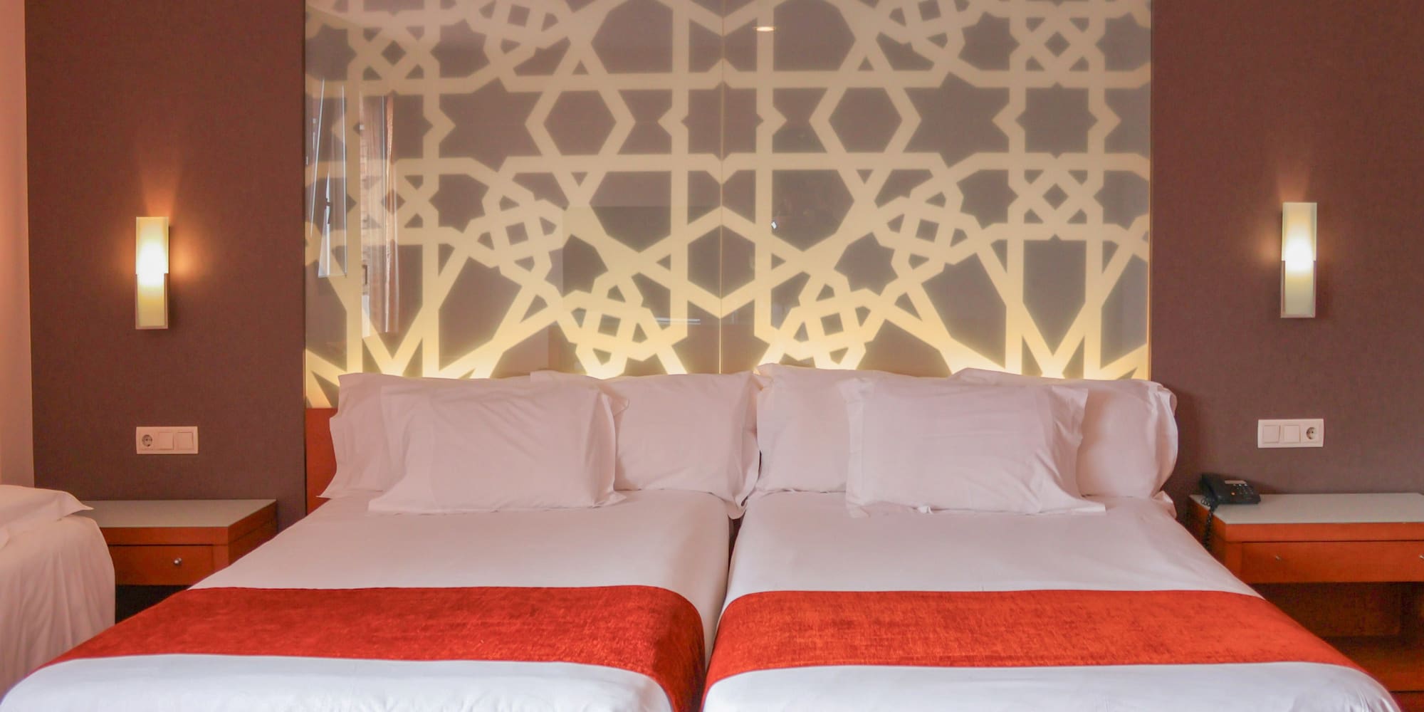 a bed with white sheets and red blankets