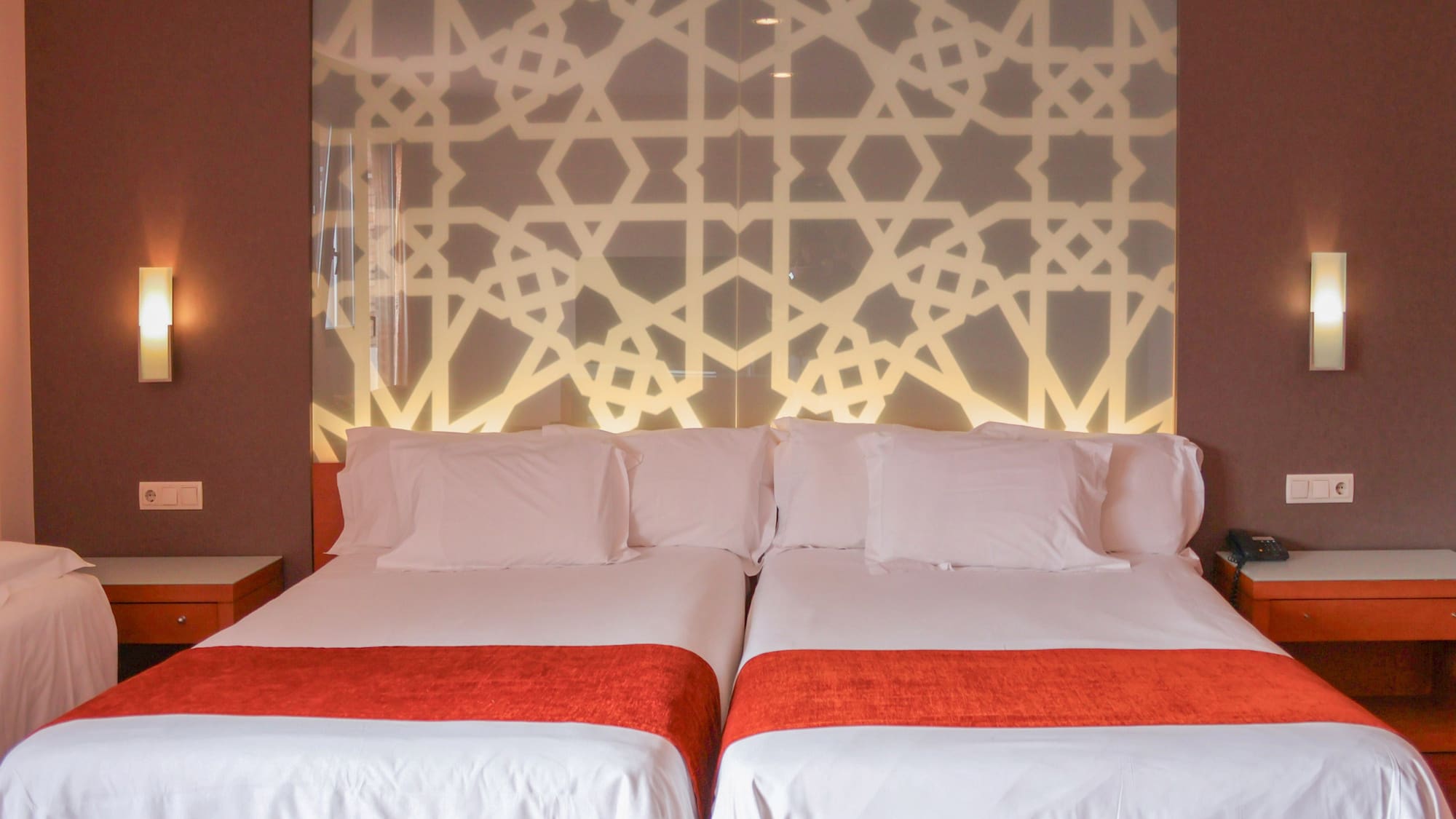 a bed with white sheets and red blankets