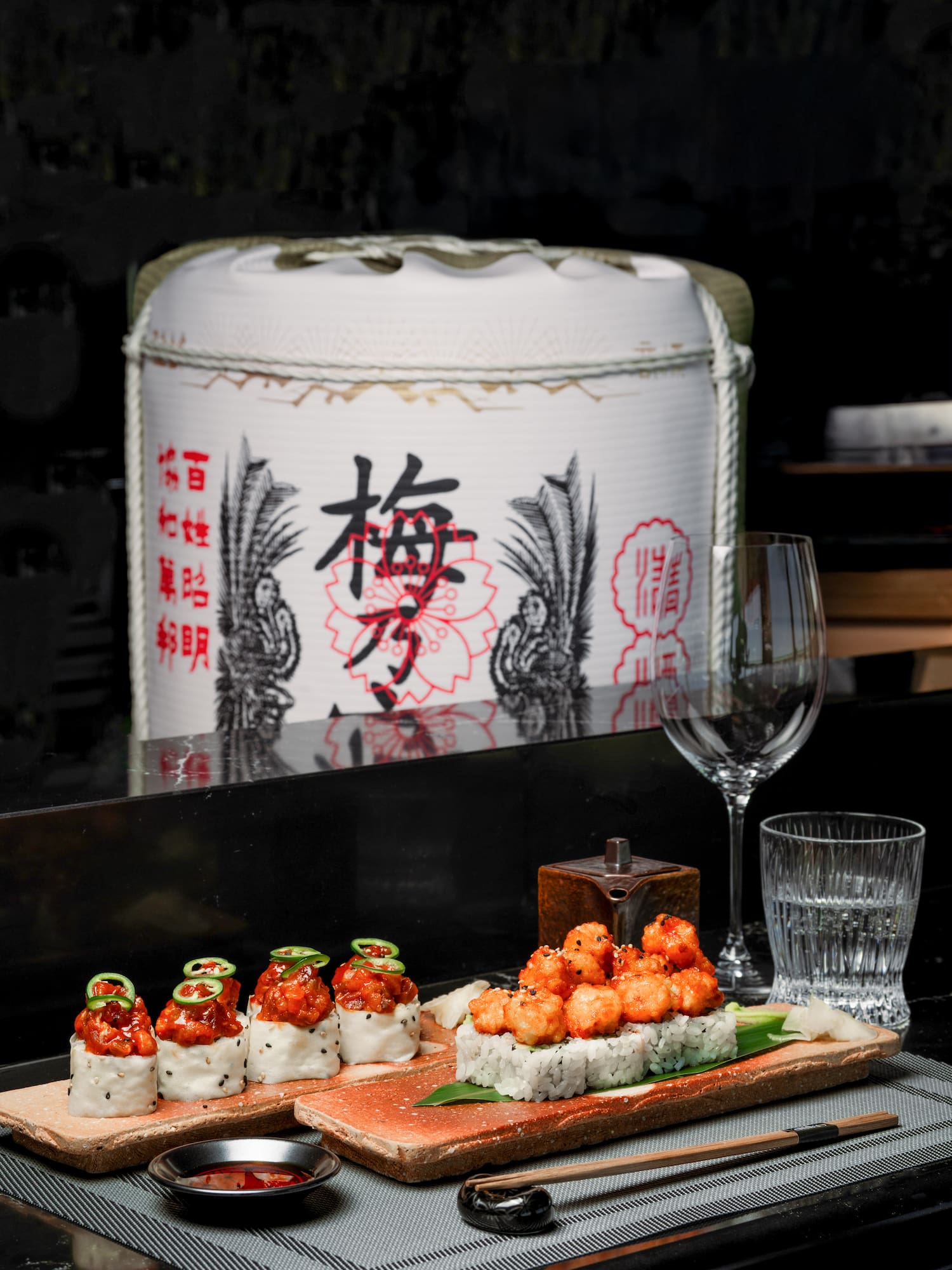 a plate of sushi with a glass and a container of water