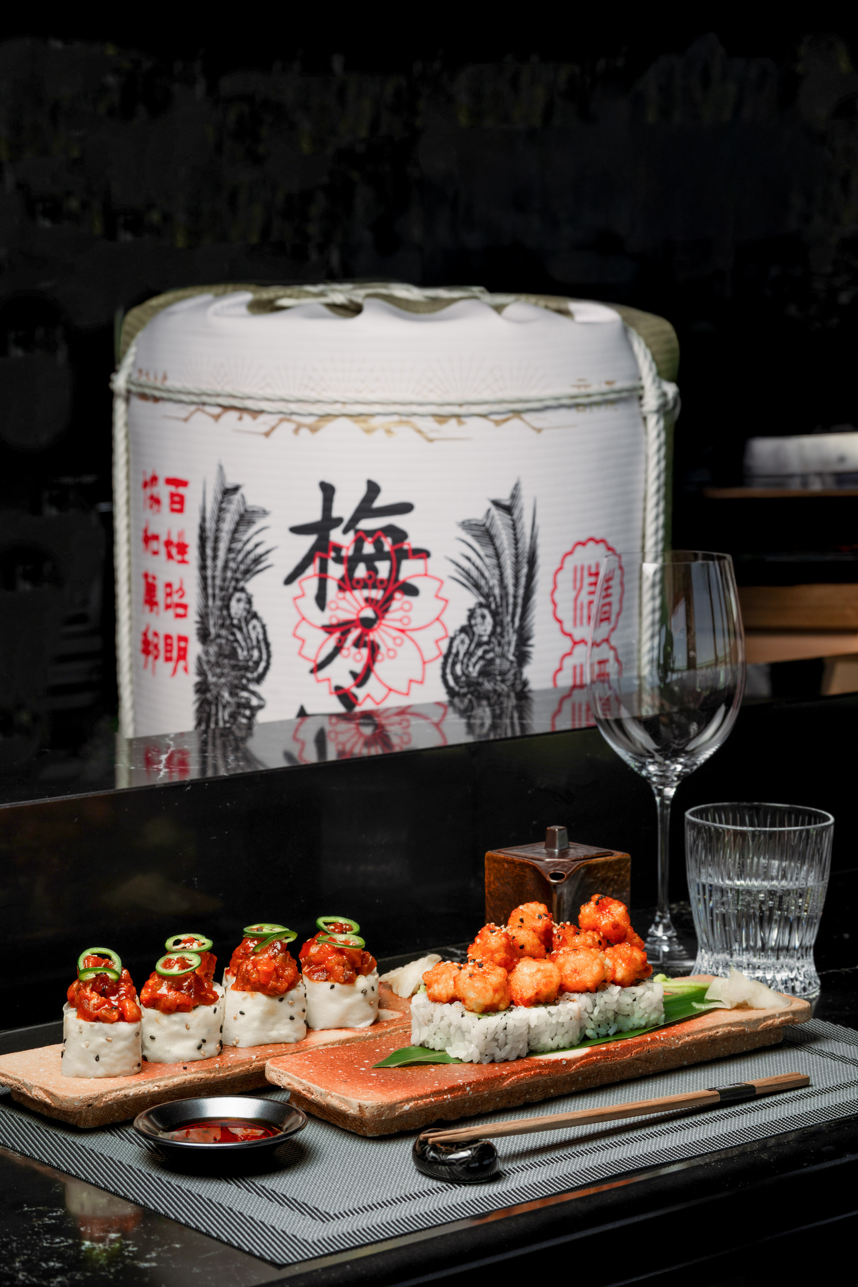 Spicy tuna and crispy shrimp sushi, sake barrel, wine, and water.