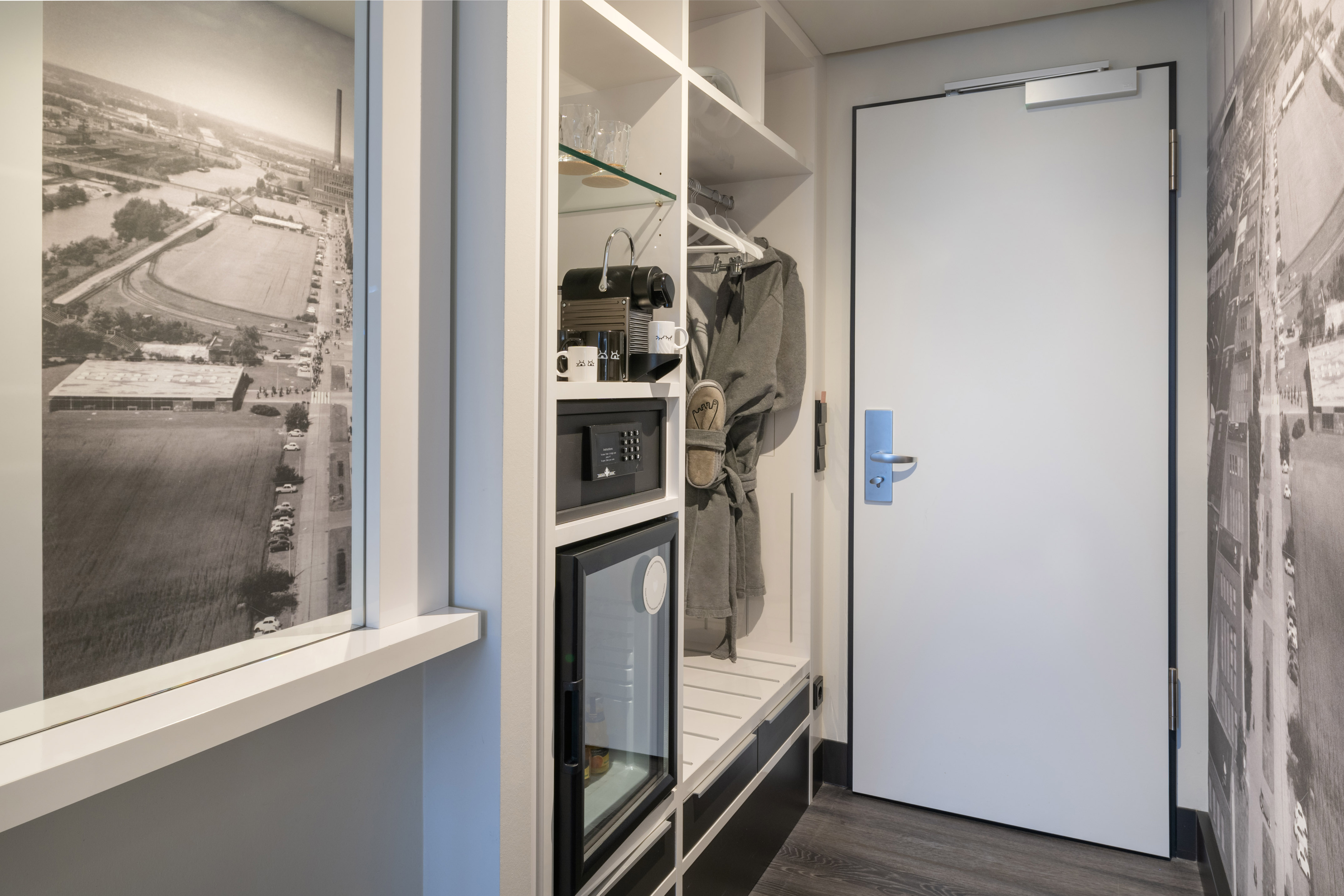 Hotel room entryway: built-in closet, Nespresso, minibar, safe, bathrobe, door.