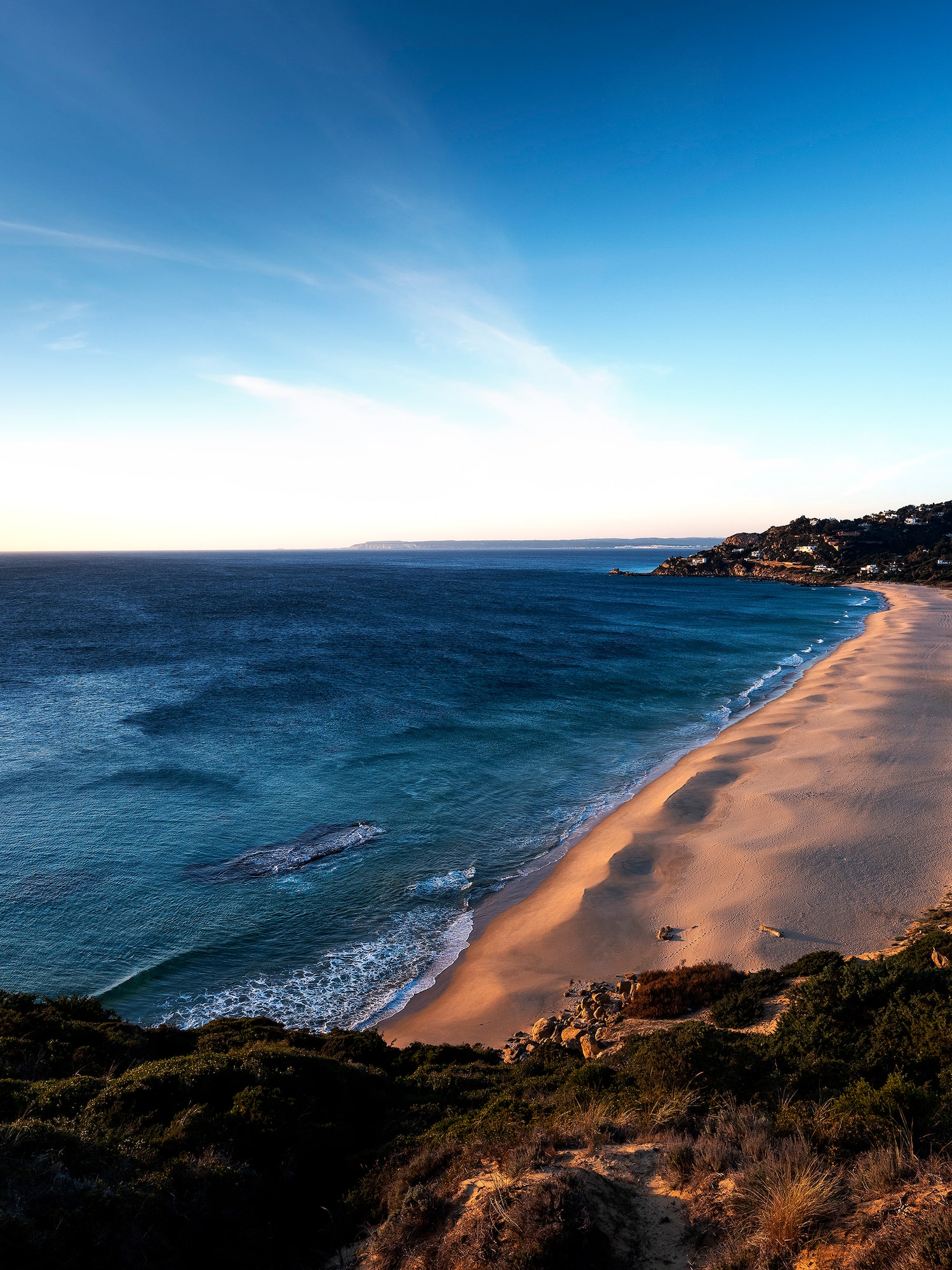 a beach with a body of water and a hill