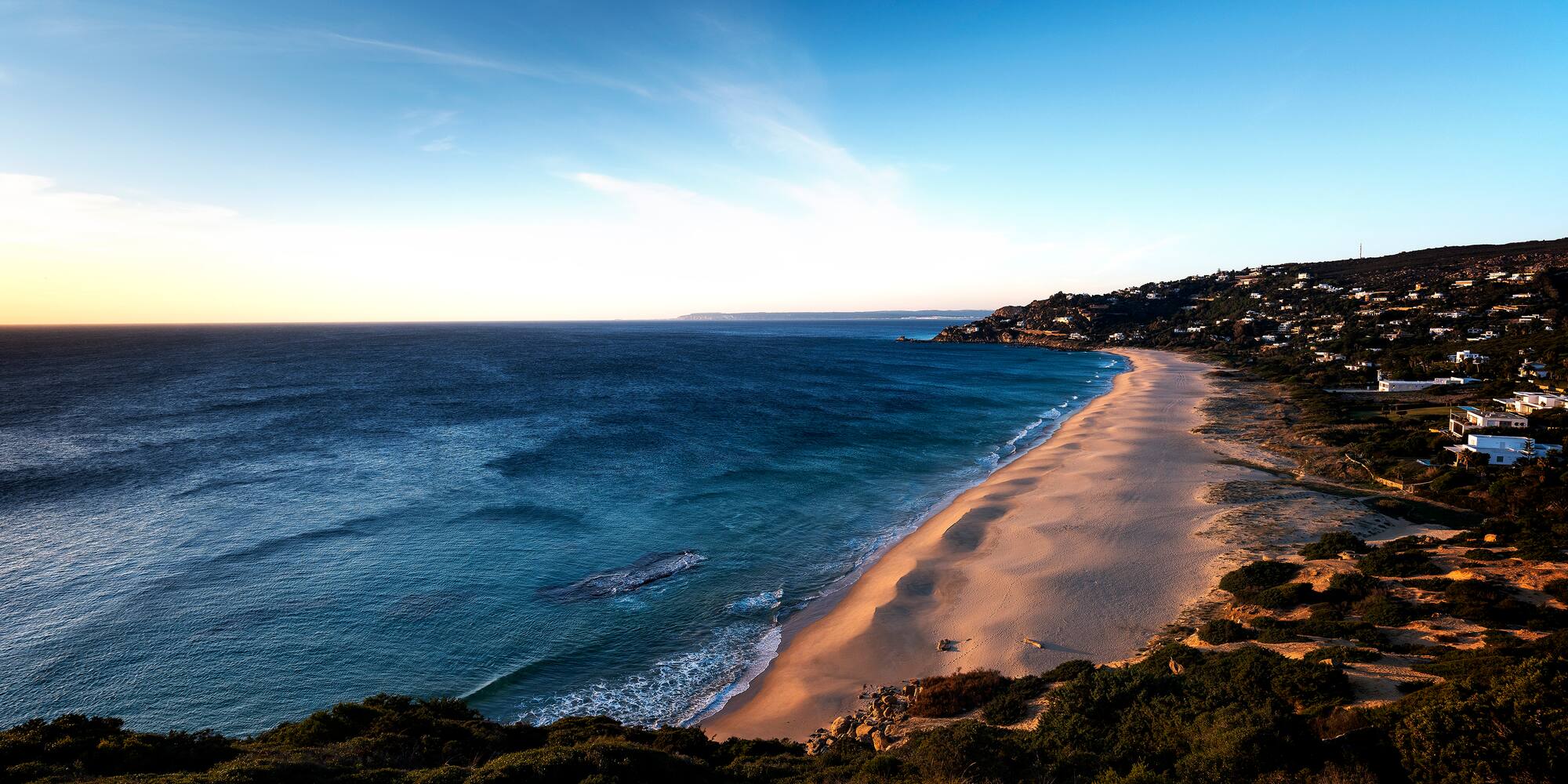 a beach with a body of water and a hill