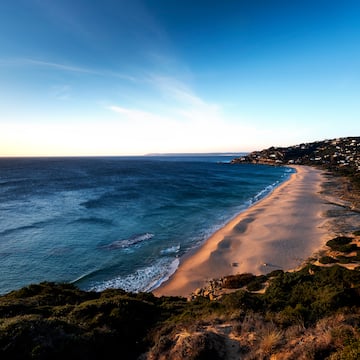 a beach with a body of water and a hill