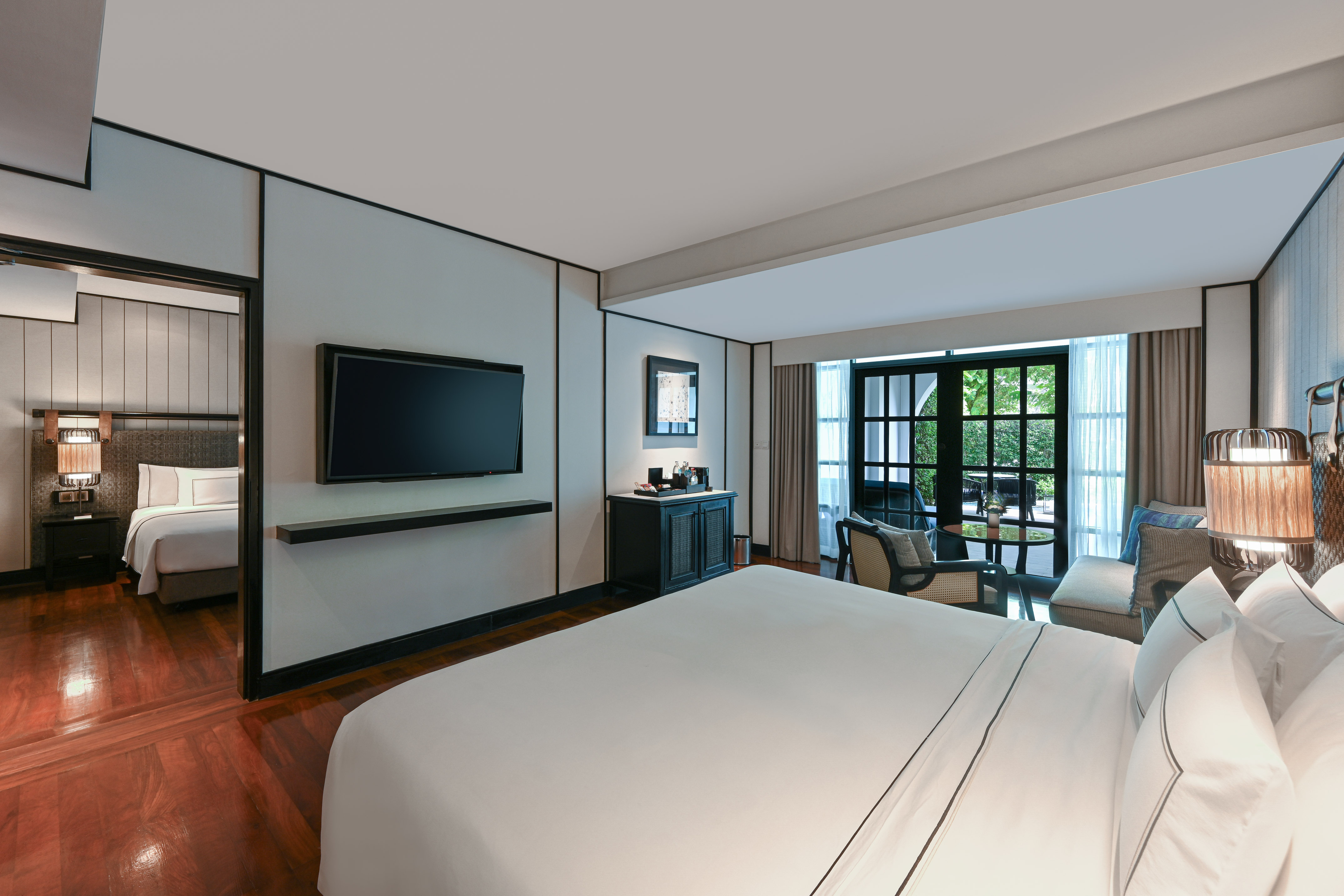 Luxurious hotel suite with king bed, balcony, and connecting room.