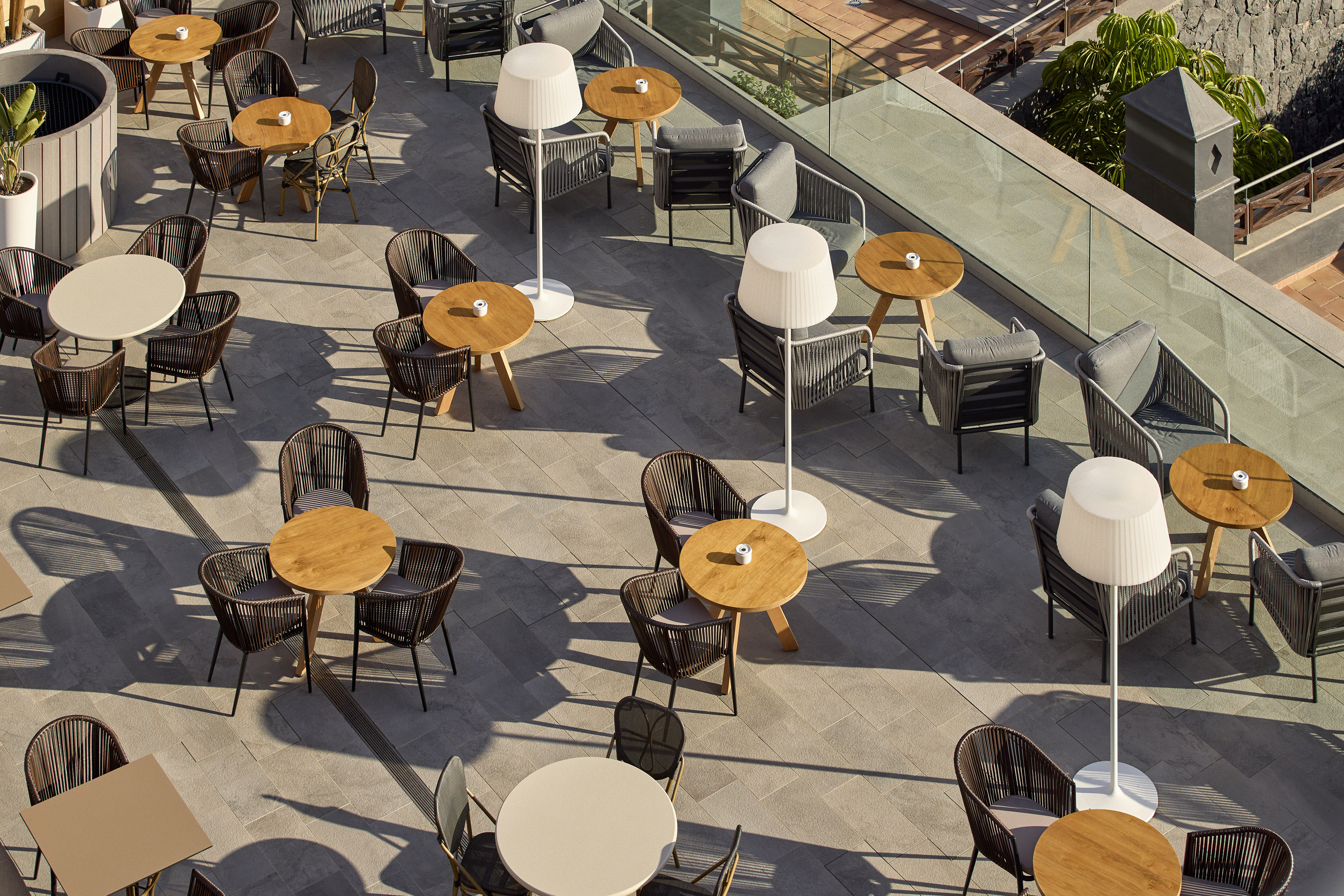 Outdoor terrace seating with modern chairs, wooden tables, and floor lamps.