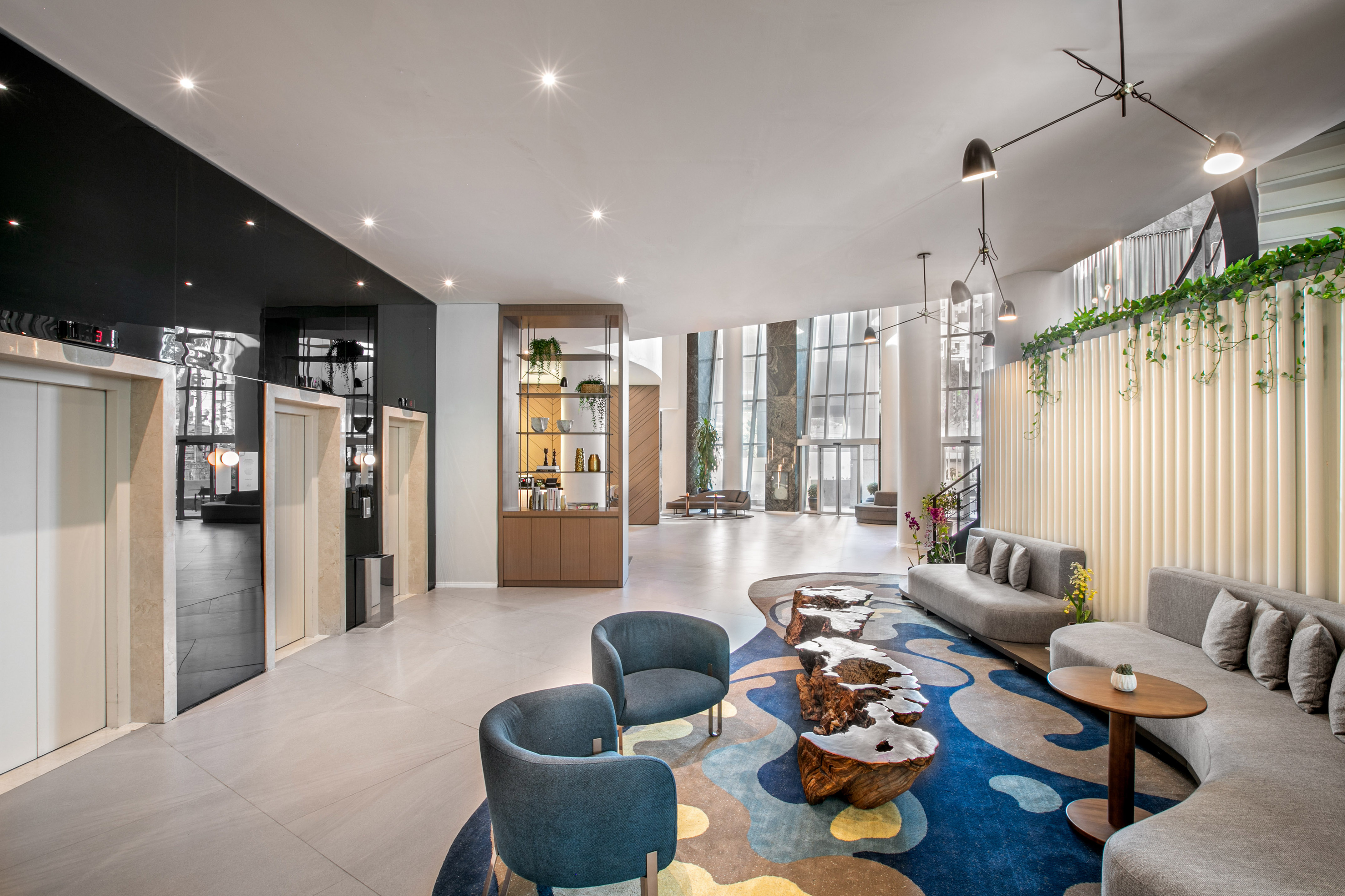 Luxury hotel lobby: vibrant abstract rug, curved sofas, modern design, elevators.