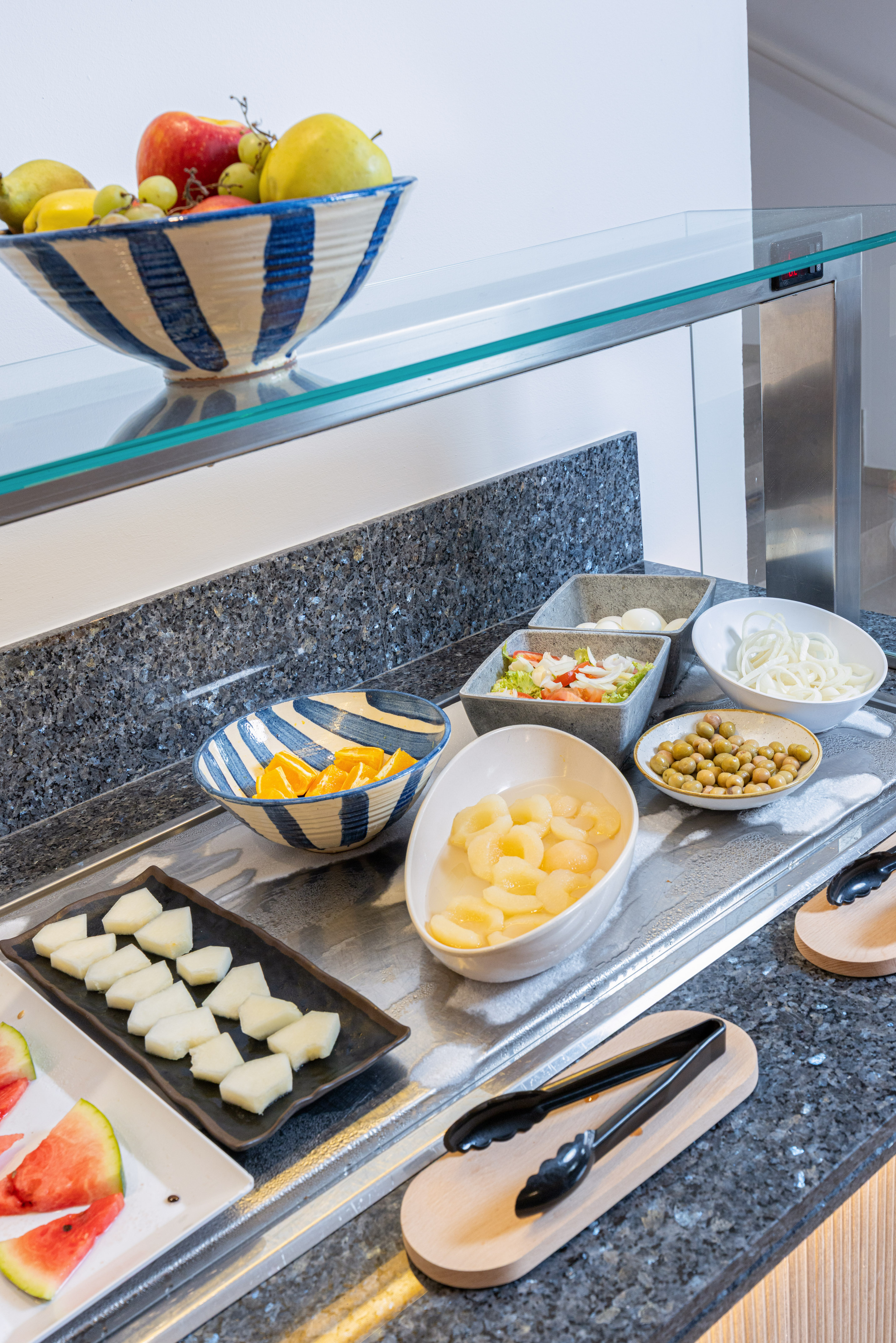 Hotel buffet featuring fresh fruit, prepared salads, olives, and melon.