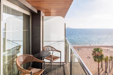 a balcony with chairs and a table overlooking a beach