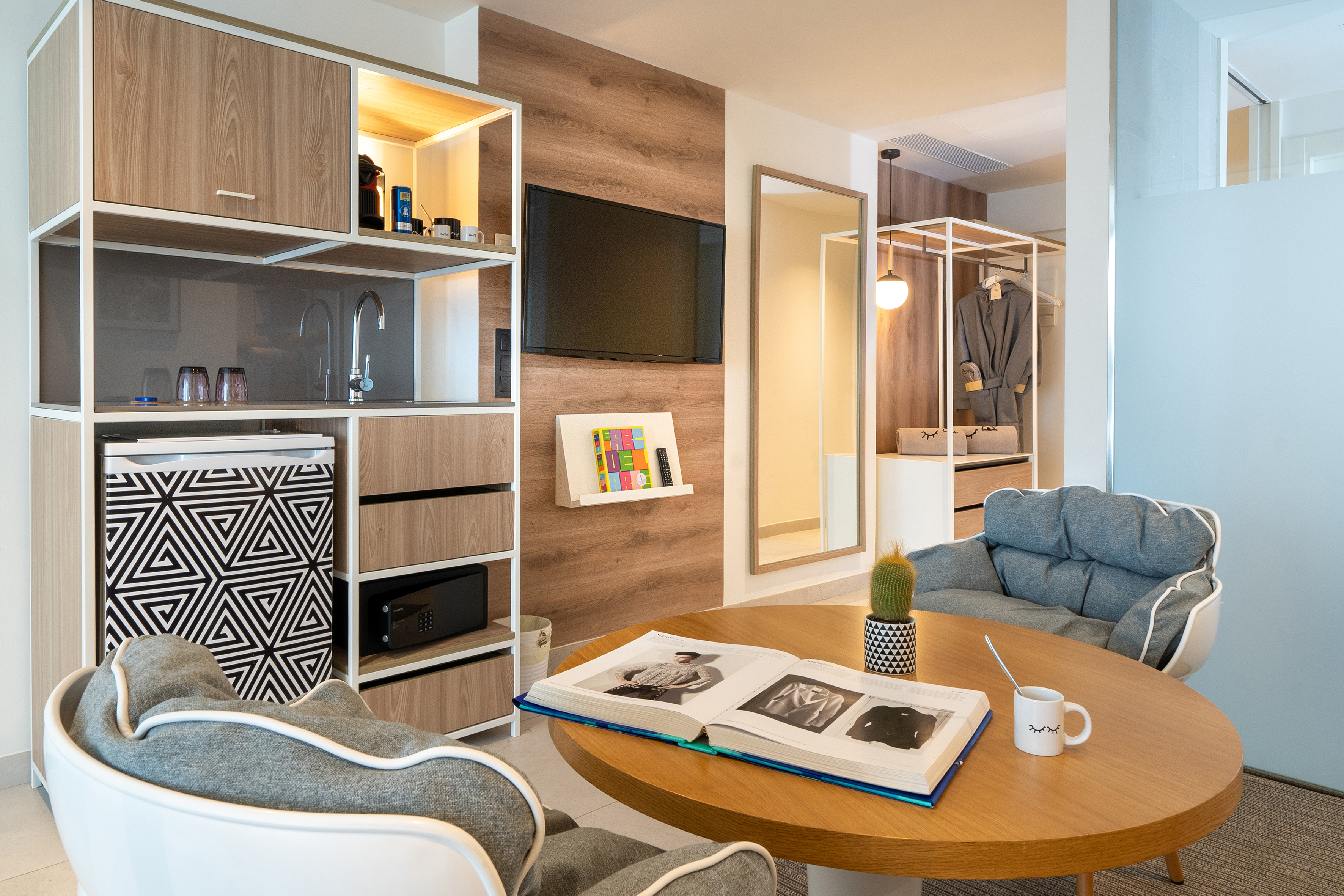 Stylish hotel studio with integrated kitchenette, TV, and cozy seating area.