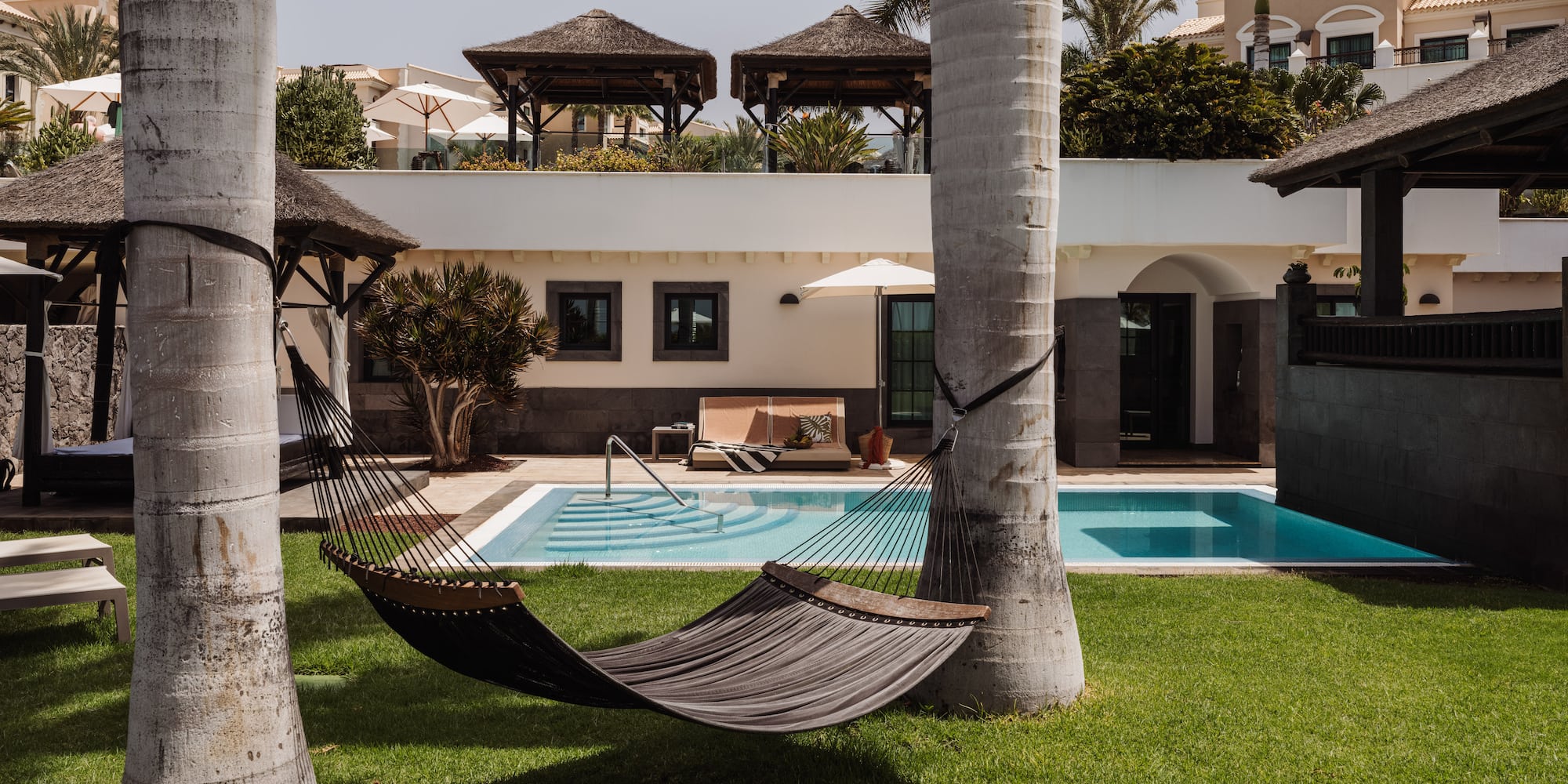 a hammock between two trees in a yard of a house