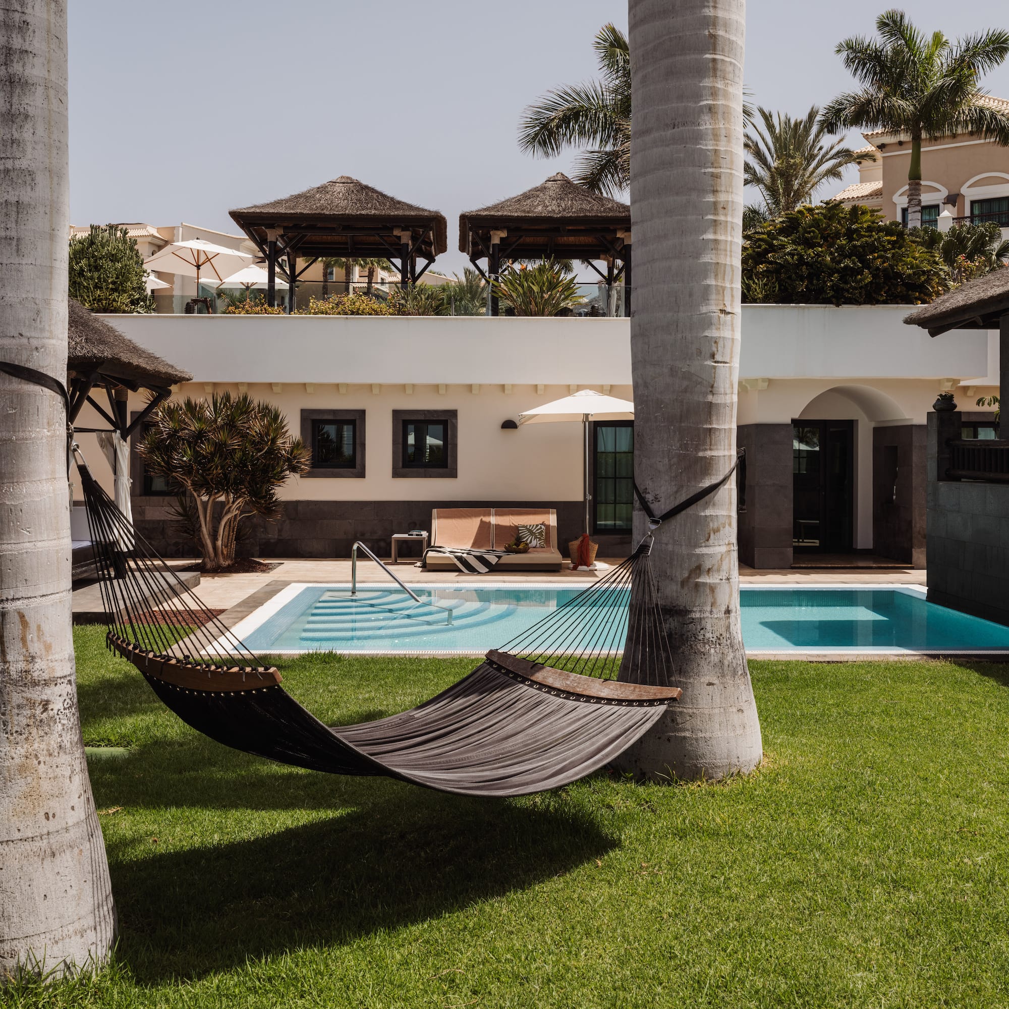 a hammock between two trees in a yard of a house