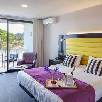 a room with a bed and a table with chairs and a glass door