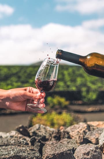 a hand holding a glass of wine being poured into a glass