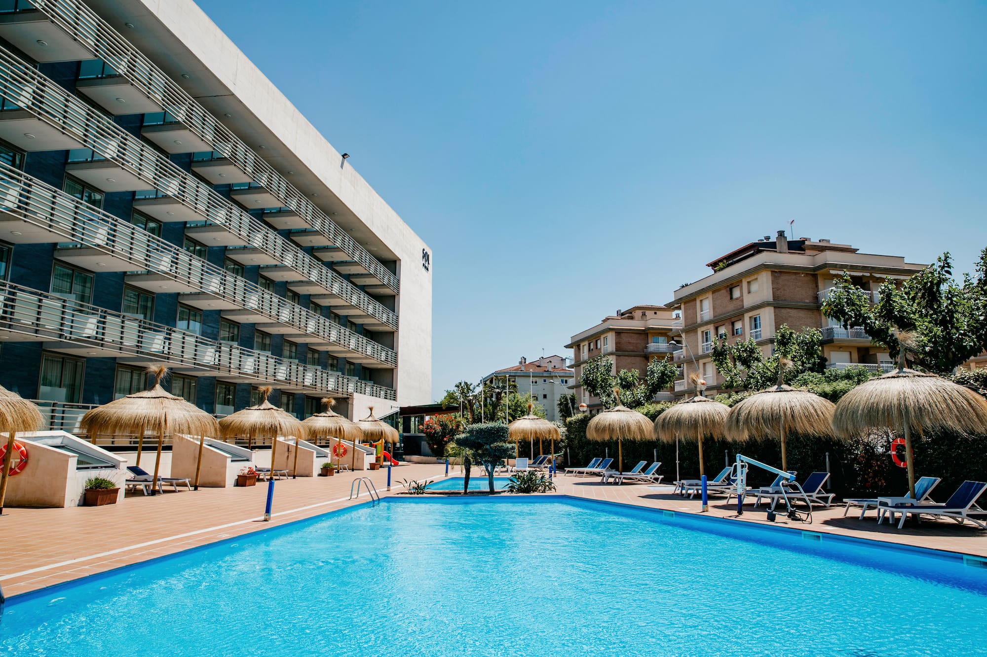 a pool with umbrellas and chairs in front of a building