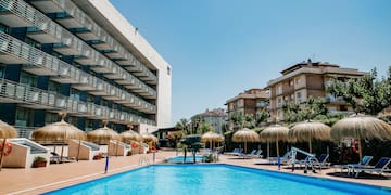 a pool with umbrellas and chairs in front of a building