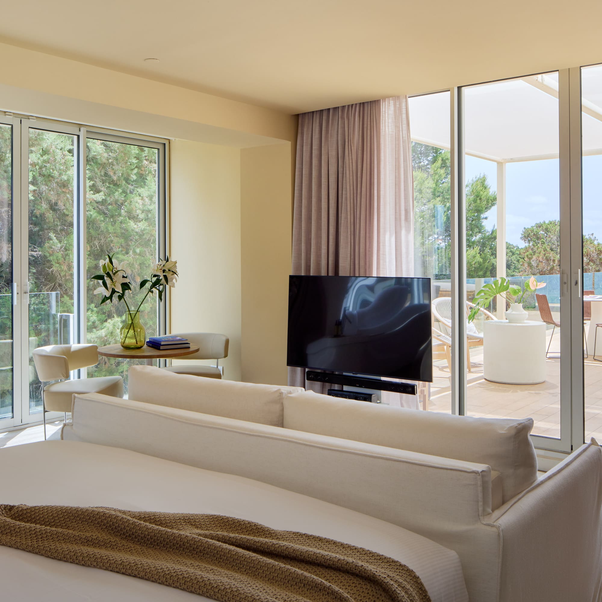 Luxury hotel suite bedroom with freestanding tub, TV, and private terrace view.
