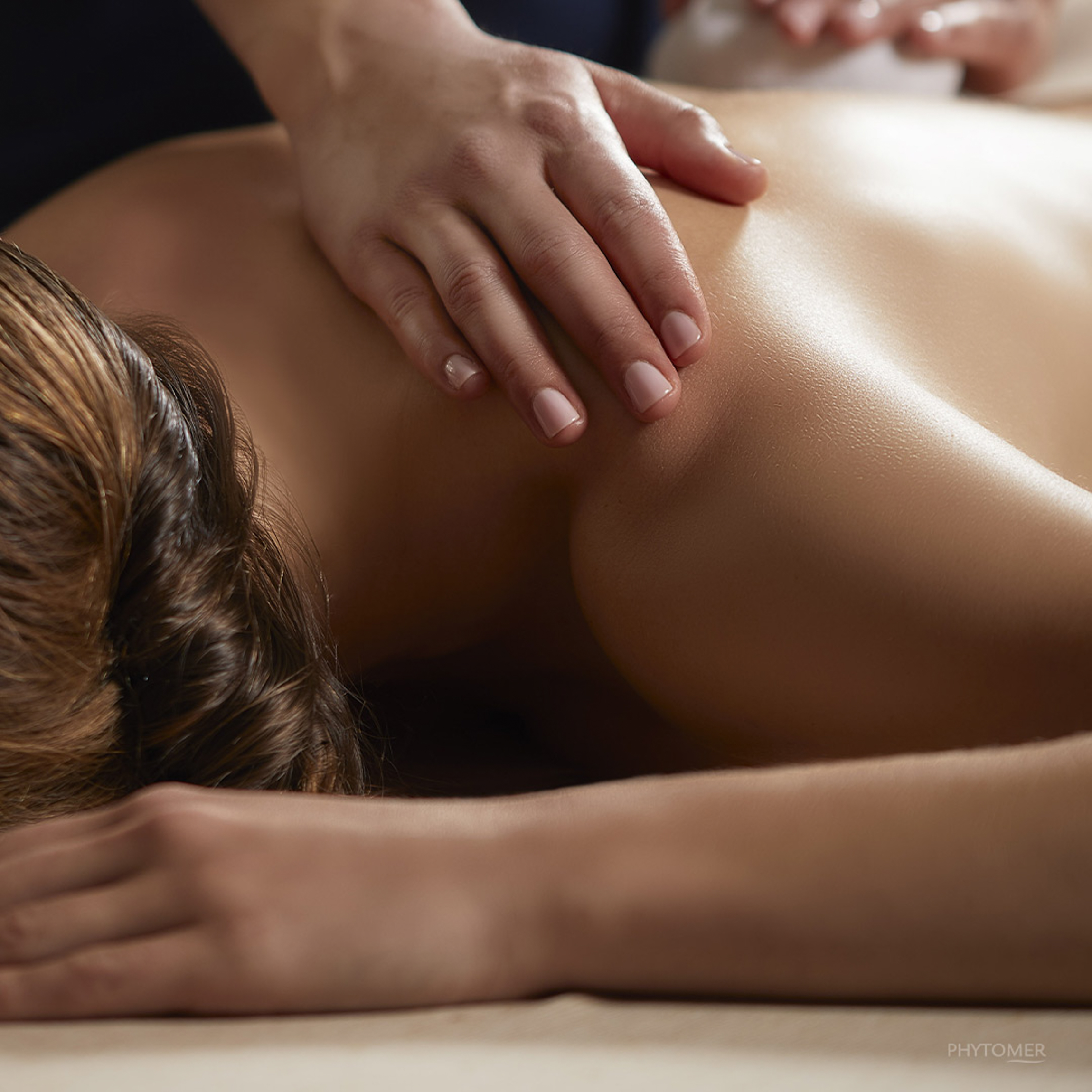 a person lying down on a bed with hands on the back