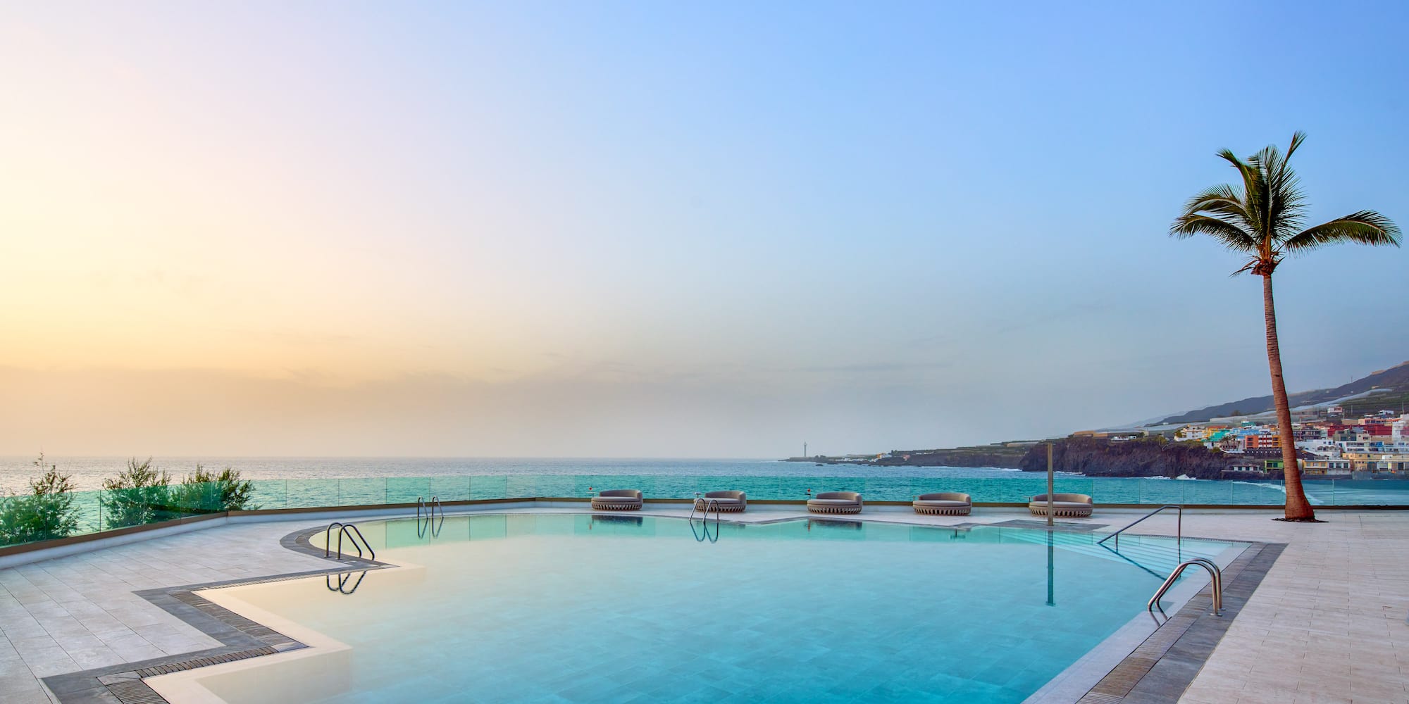 a pool with chairs and a body of water