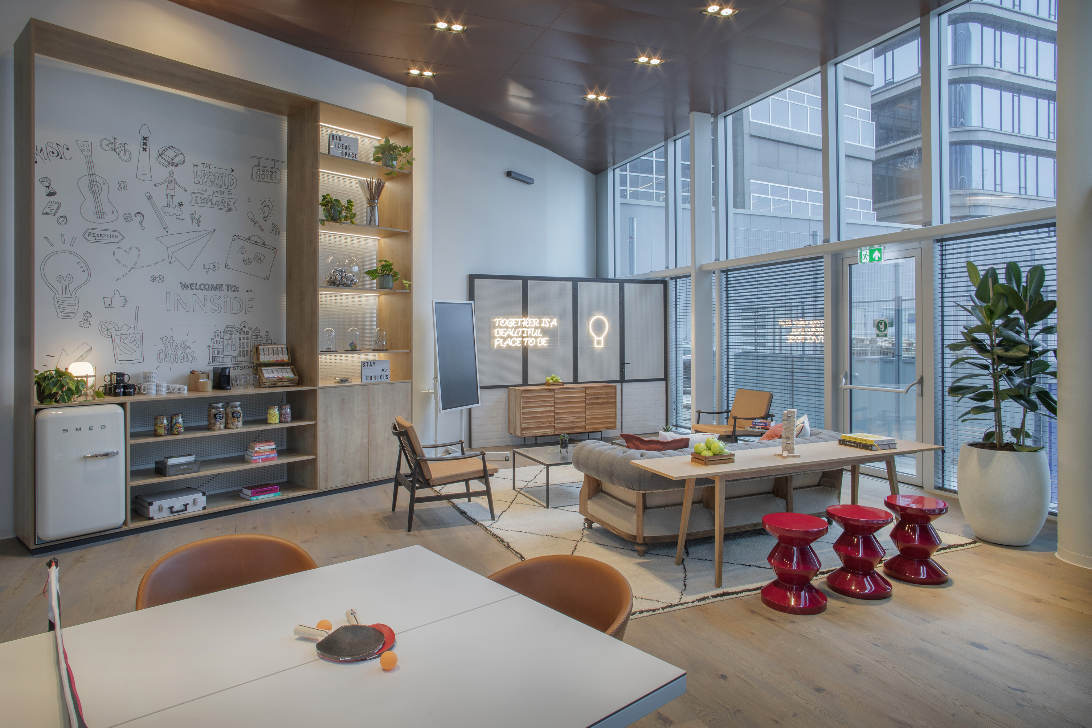 Modern Innside hotel lounge with playful mural, ping pong table, and neon art.